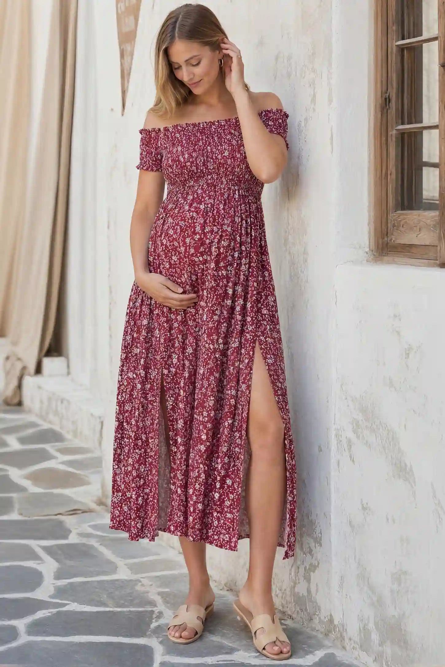 Floral off-shoulder smocked bodice maxi maternity dress in burgundy featuring smocked neckline in front view on a pregnant model