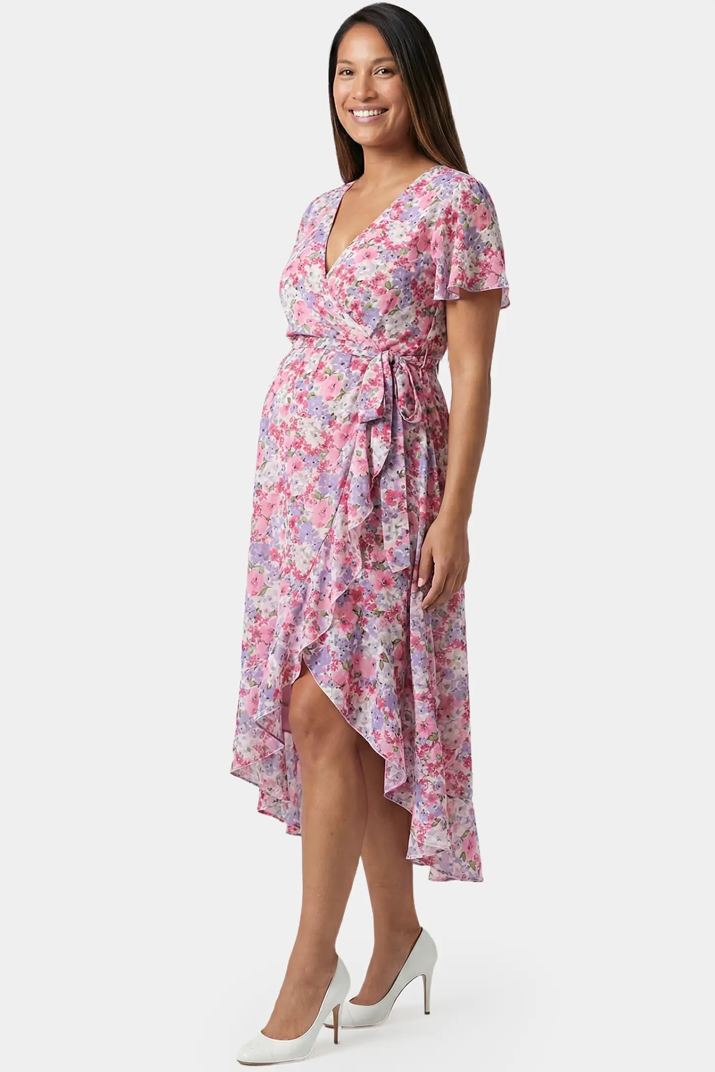 Floral V-neck ruffled hem midi maternity dress in pink featuring short-sleeve and tie waist in full body side view on a pregnant model