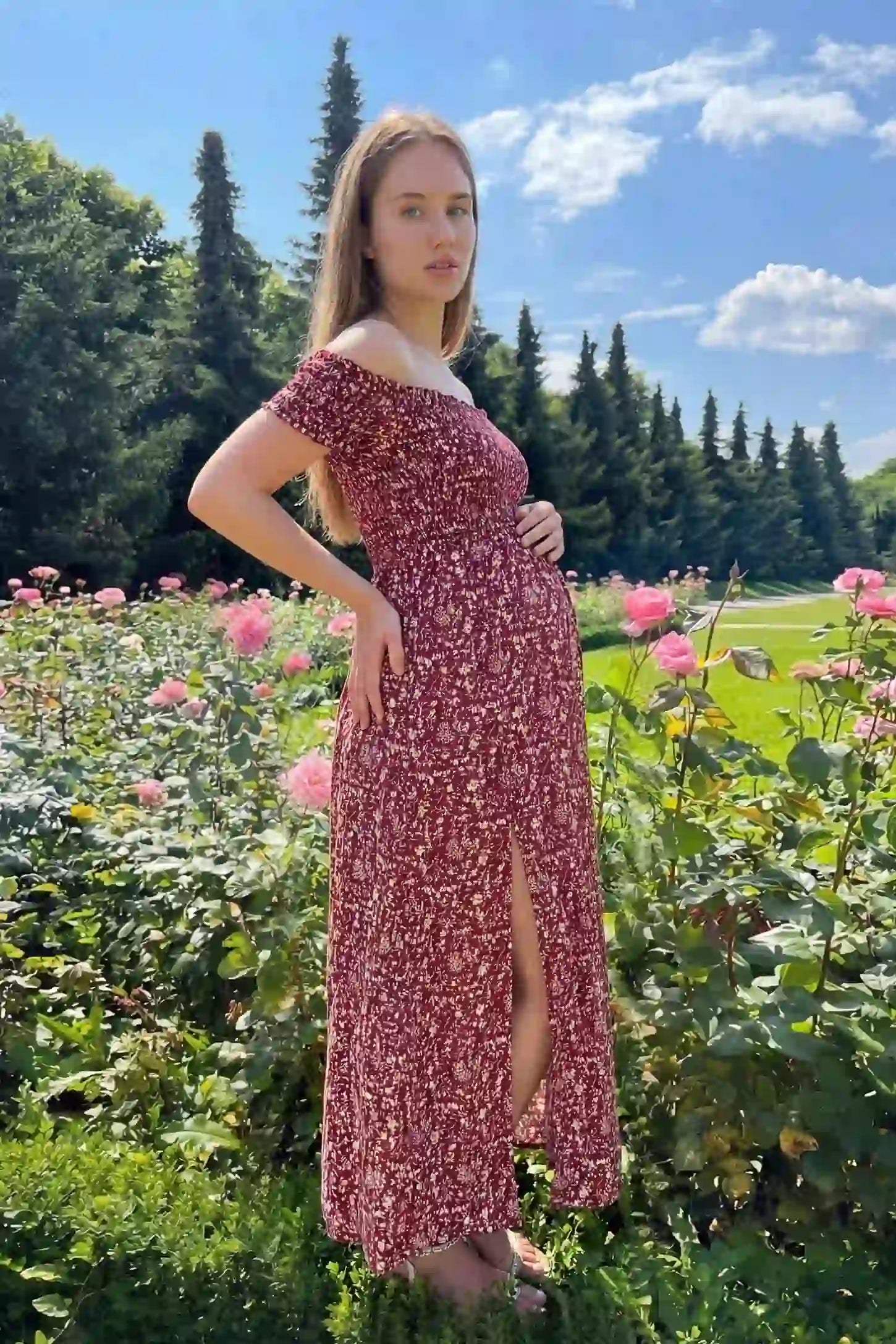 Floral Off-Shoulder Smocked Bodice Maxi Maternity Dress Floral off-shoulder smocked bodice maxi maternity dress in red featuring smocked neckline in front view on a editorial lifestyle model