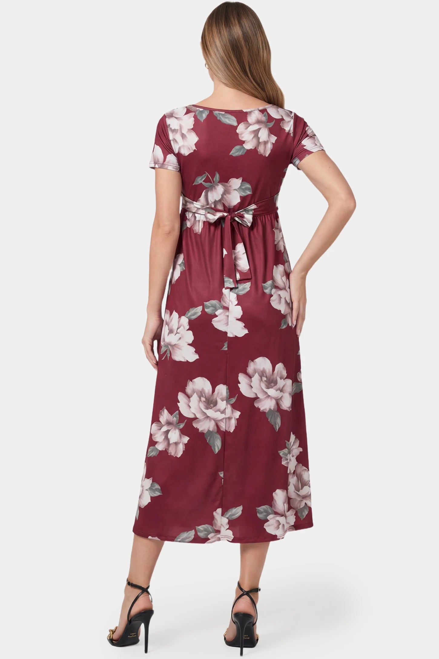 Floral V-Neck Wrap High-Low Maxi Maternity Dress Floral V-neck wrap high-low maxi maternity dress in wine red floral featuring short sleeves and adjustable tie in back view on a pregnant model