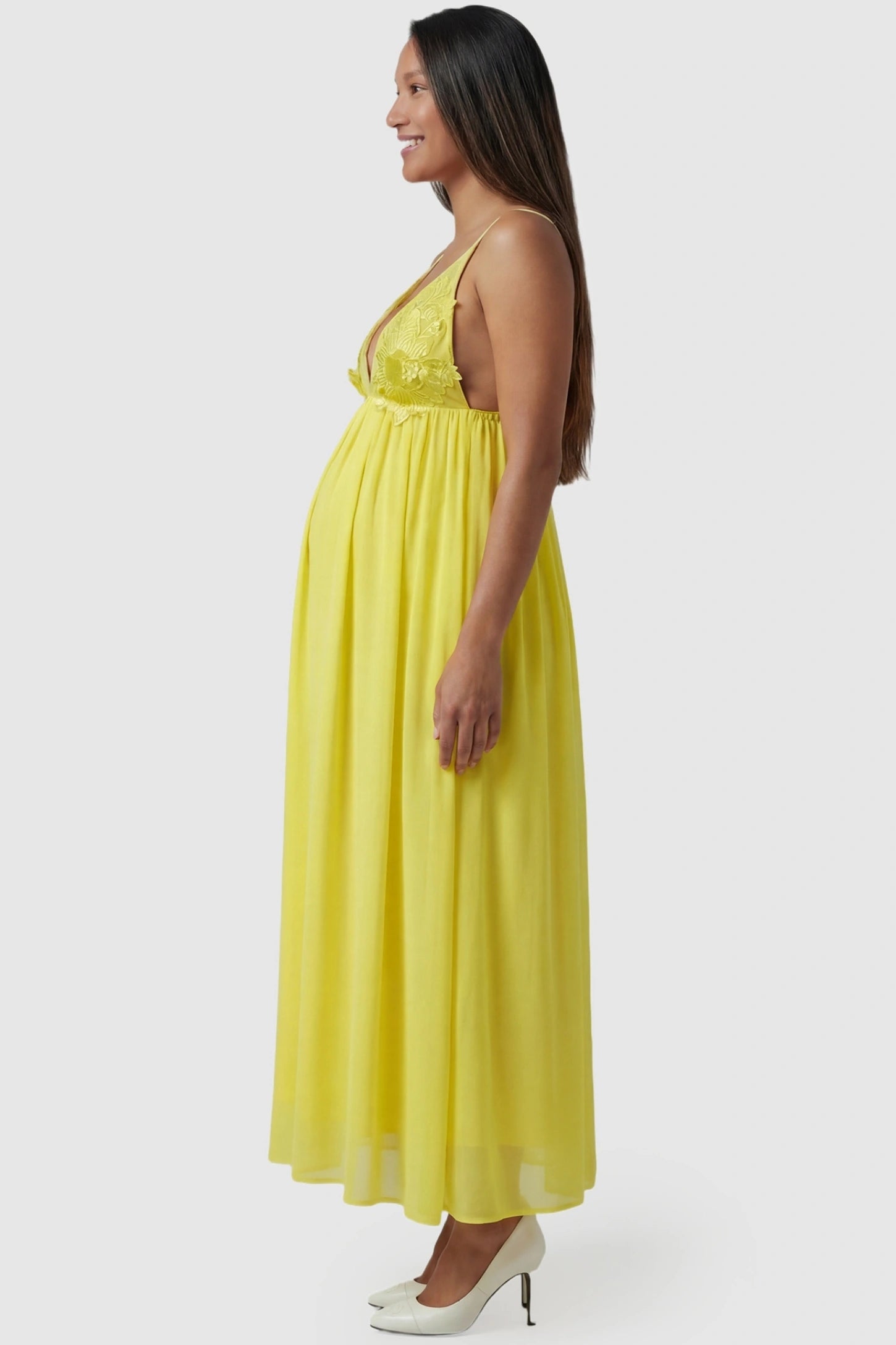 Floral Embroidered Chiffon Maternity Maxi Dress in Yellow featuring a multi-layered skirt on a pregnant model side view.