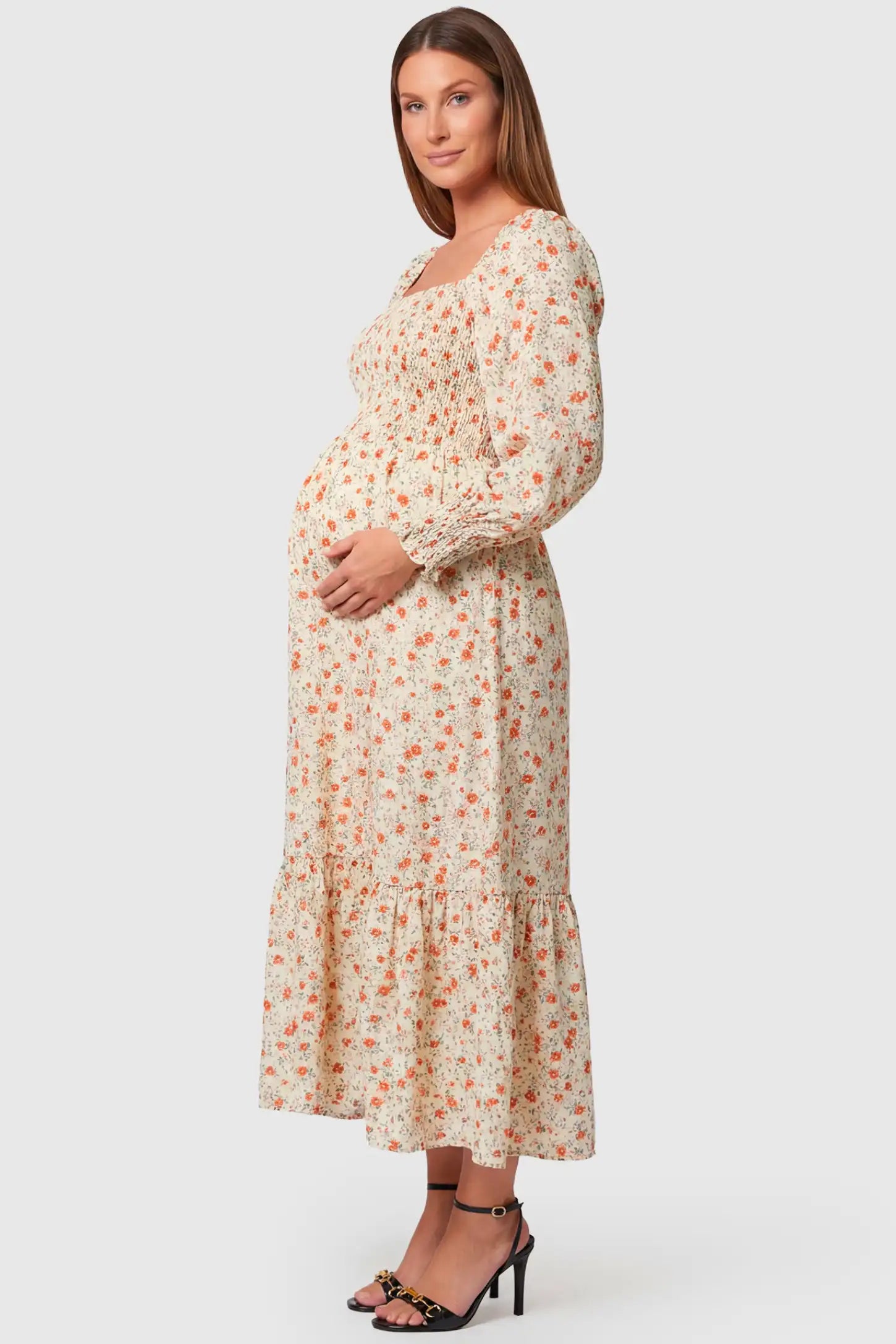 Floral Smocked Tiered Maternity Midi Dress Floral Smocked Tiered Maternity Midi Dress in white floral print featuring square neckline, puff sleeves, and tiered midi skirt on pregnant model, side view