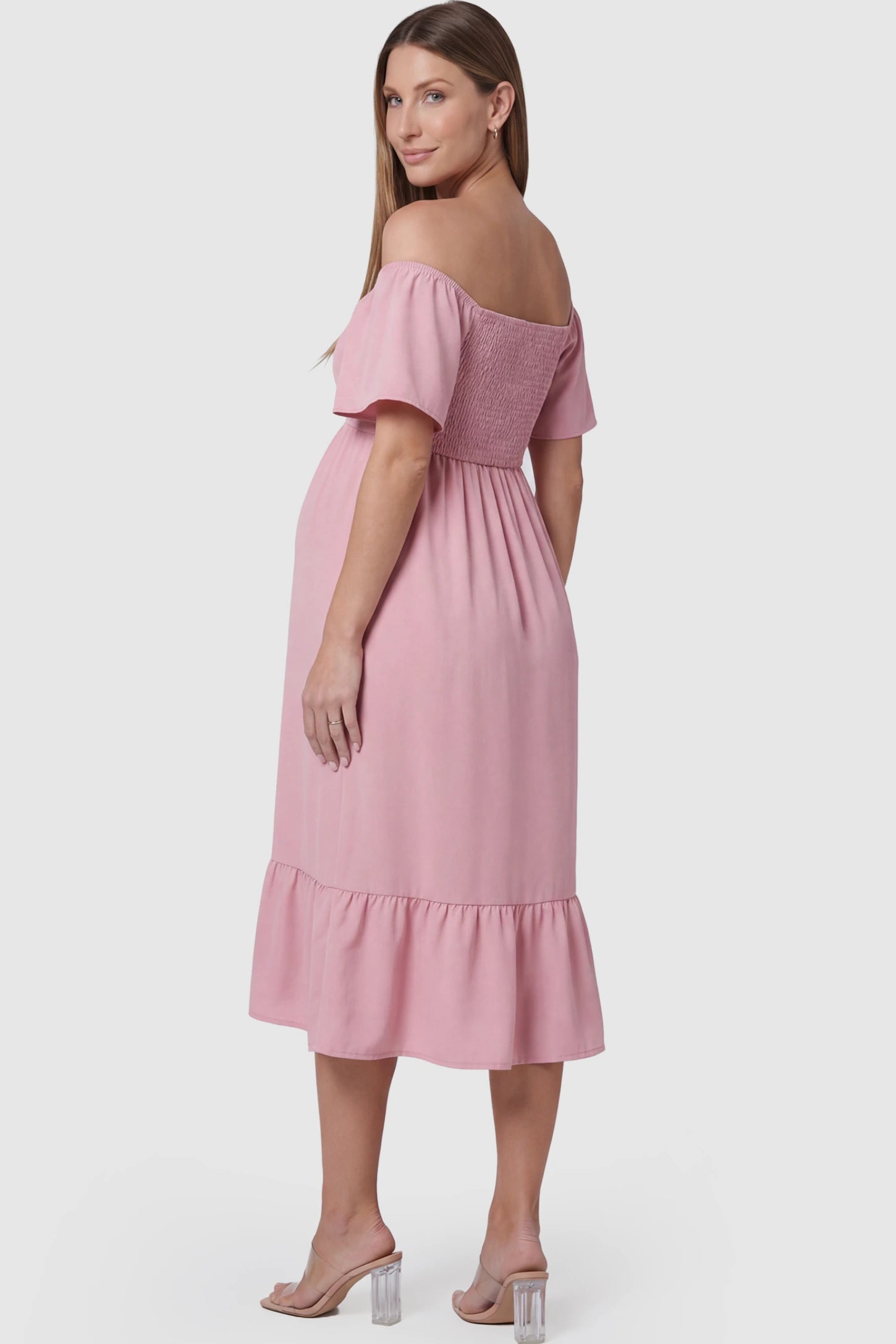 Flutter-Sleeve Smocked Maternity Midi Dress Flutter Sleeve Smocked Maternity Midi Dress in light pink color featuring a flowy silhouette and smocked bodice on a pregnant model.
