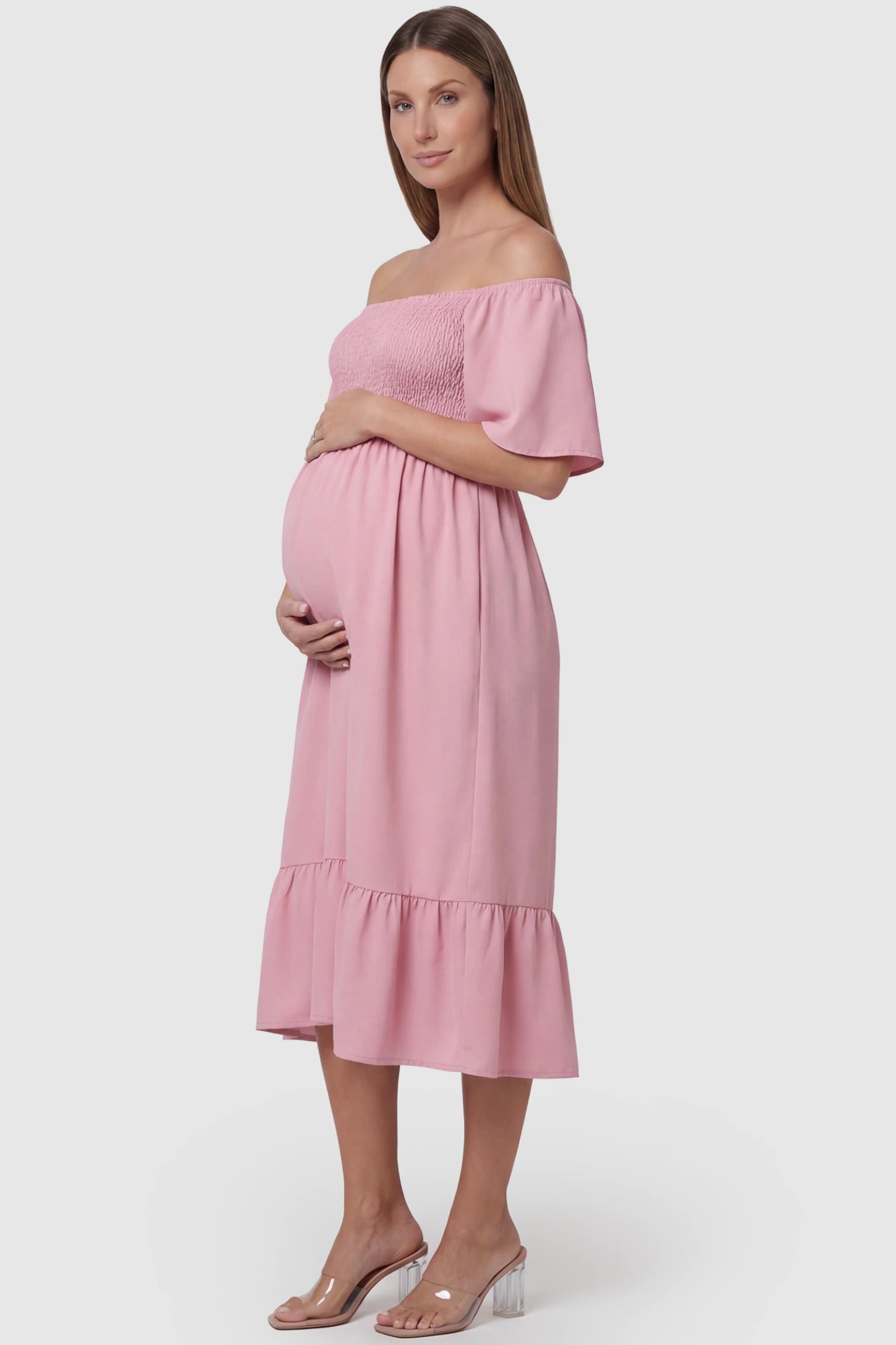 Flutter-Sleeve Smocked Maternity Midi Dress Flutter Sleeve Smocked Maternity Midi Dress in light pink color featuring a flowy silhouette and smocked bodice on a pregnant model.