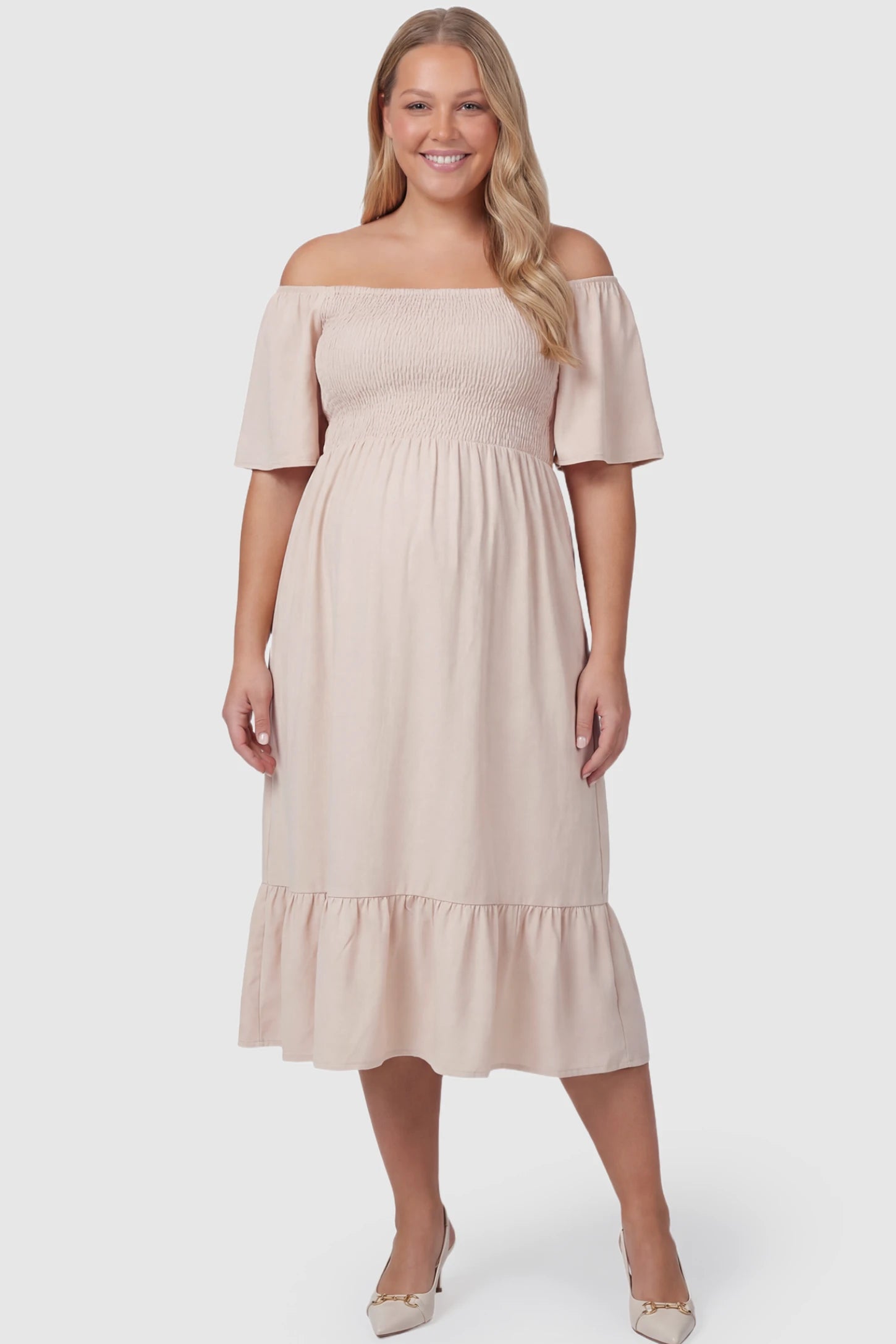 Flutter-Sleeve Smocked Maternity Midi Dress Flutter Sleeve Smocked Maternity Midi Dress in skin color featuring a flowy silhouette and smocked bodice on a plus size pregnant model.