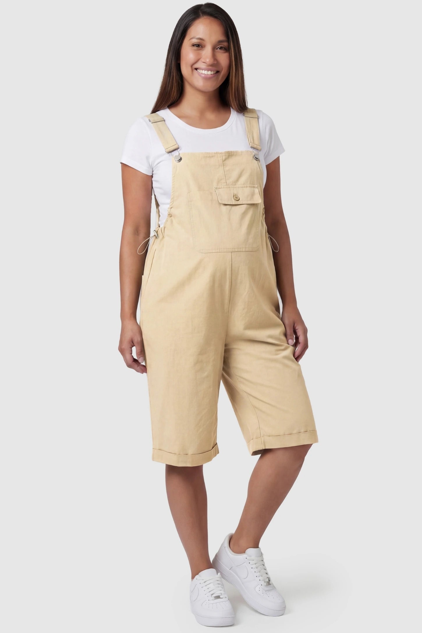 Oversized Front Pocket Maternity Overalls Shorts Oversized Front Pocket Maternity Overalls Shorts in Khaki featuring adjustable straps on a pregnant model.