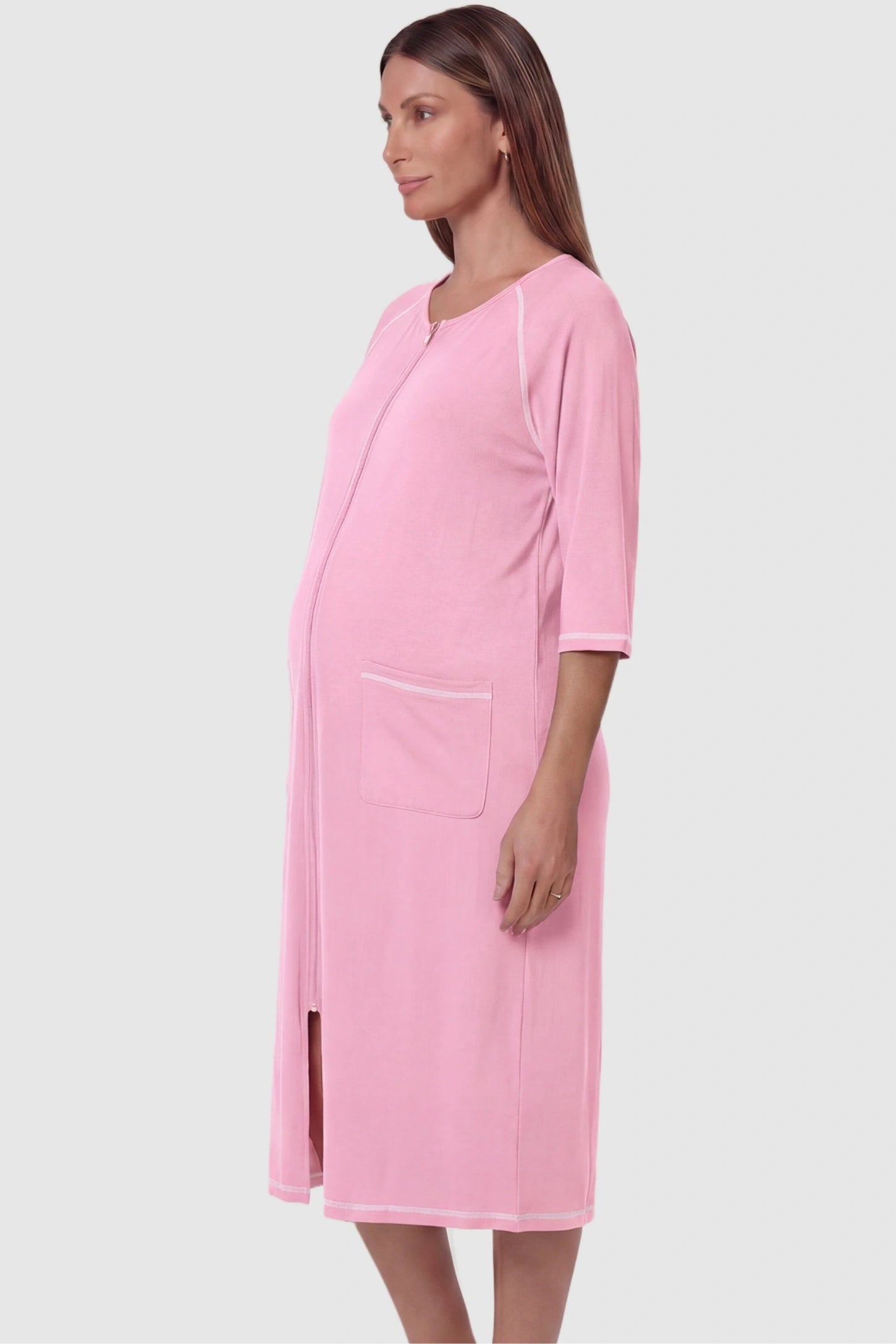 Front Zipper Three-Quarter Sleeve Midi Maternity & Nursing Dress Front zipper three-quarter sleeve midi maternity and nursing dress in pink featuring functional pockets and three-quarter sleeves in side view on a pregnant model
