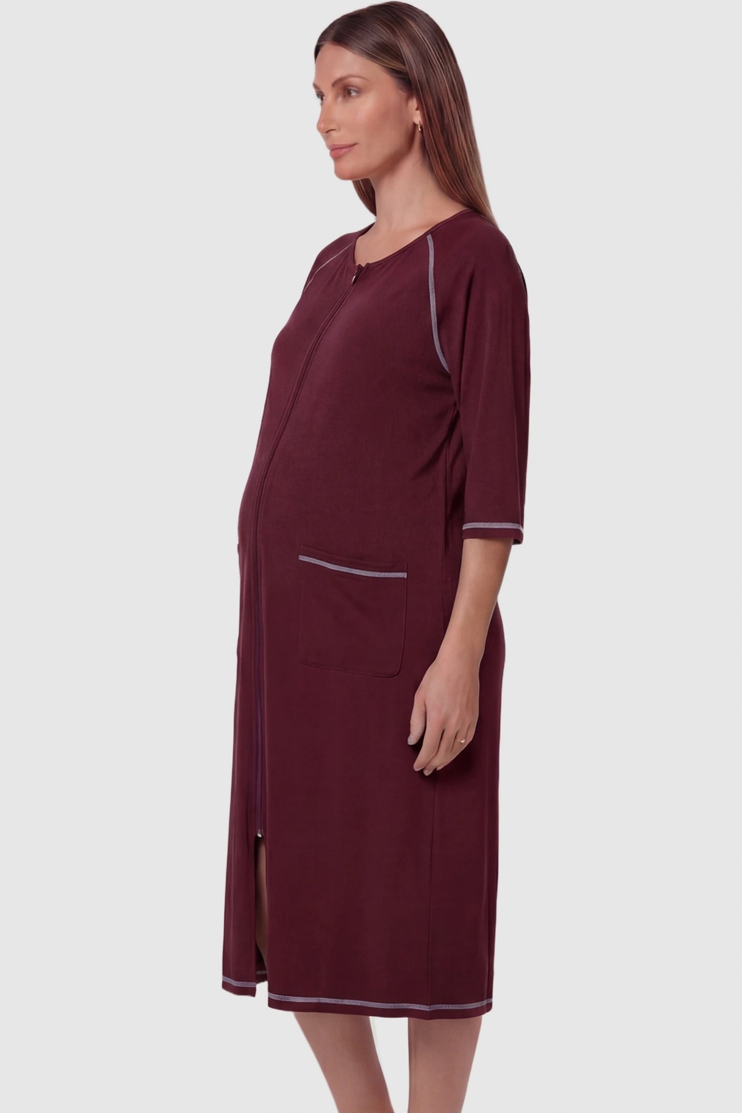 Front Zipper Three-Quarter Sleeve Midi Maternity & Nursing Dress Front zipper three-quarter sleeve midi maternity and nursing dress in wine red featuring functional pockets and three-quarter sleeves in side view on a pregnant model