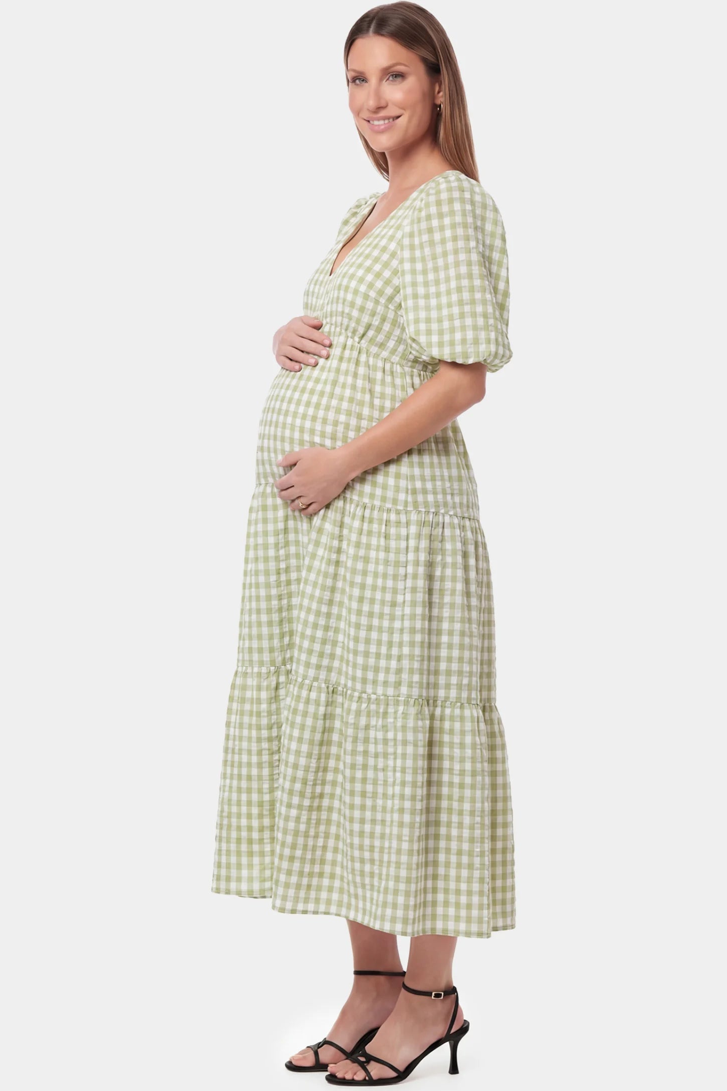 Gingham V-Neck Tiered Maxi Maternity Dress Gingham V-Neck Tiered Maxi Maternity Dress in Green featuring a flowing tiered silhouette in side view on a pregnant model