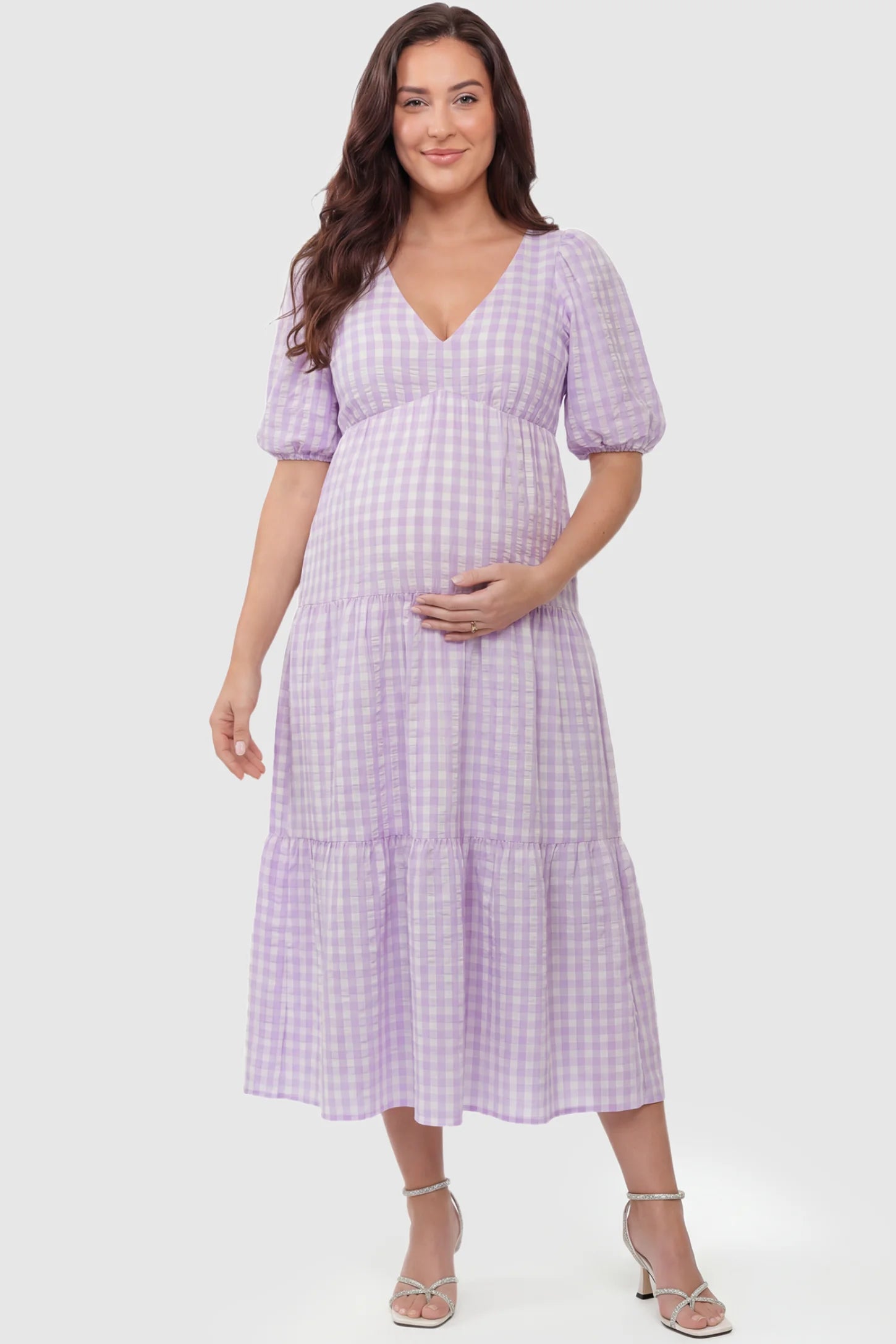 Gingham V-Neck Tiered Midi Maternity Dress Gingham V-Neck Tiered Midi Maternity Dress in lavender featuring a flowing tiered silhouette in front view on a plus-size model