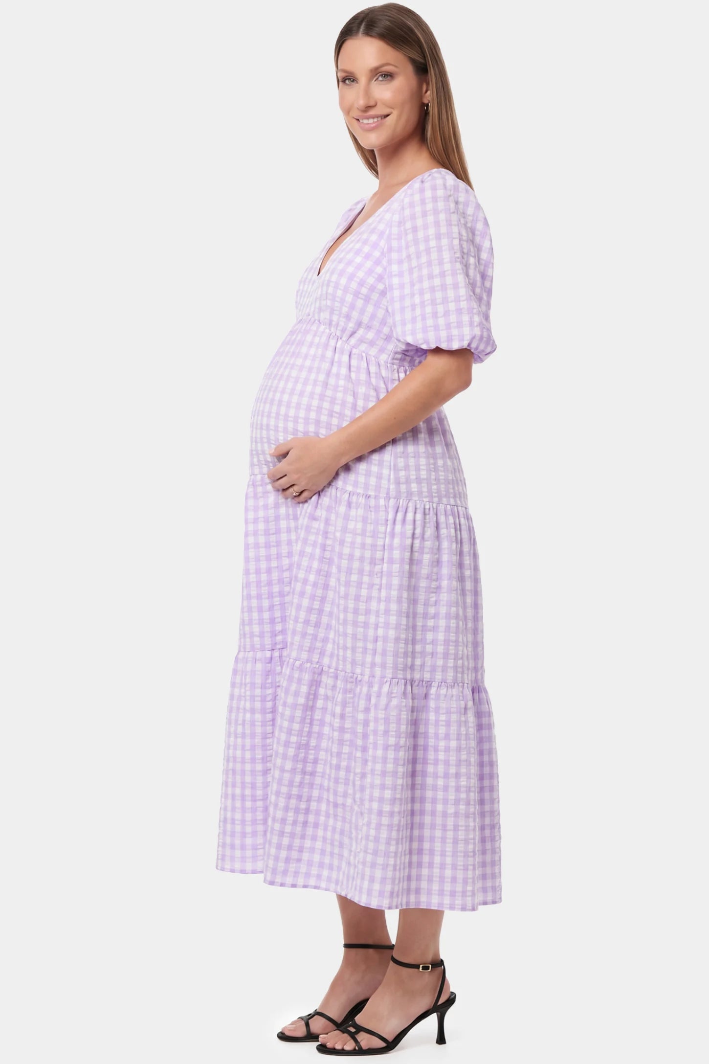 Gingham V-Neck Tiered Maxi Maternity Dress in lavender featuring a flowing tiered silhouette in side view on a pregnant model