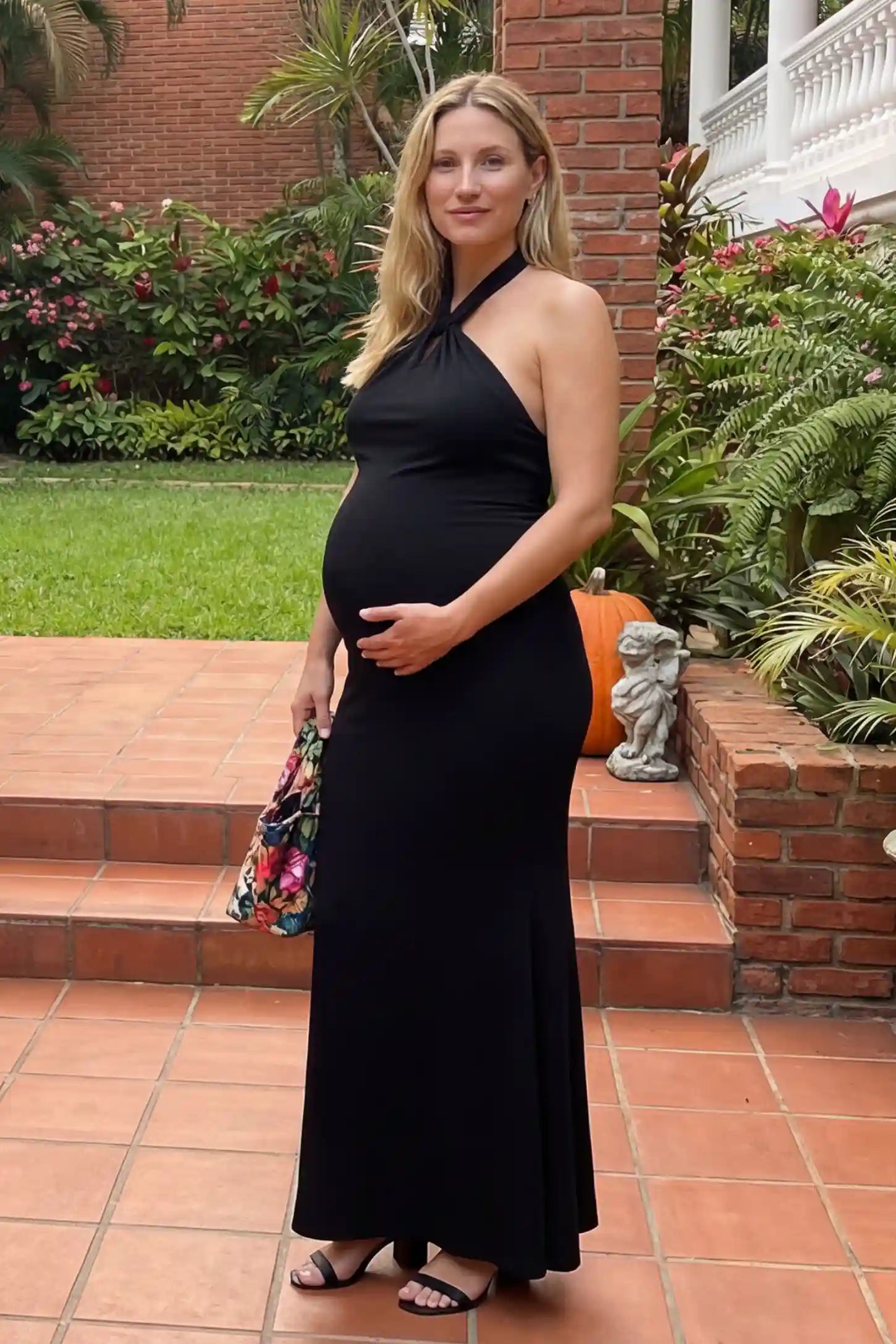 Halter Neck Sleeveless Maternity Maxi Dress in black featuring a backless halter neckline and fitted maxi silhouette on a pregnant model.
