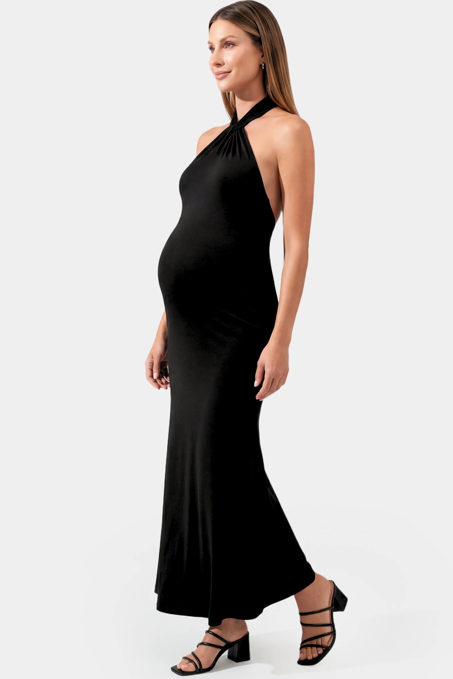 Halter Neck Sleeveless Maternity Maxi Dress in black featuring a backless halter neckline and fitted maxi silhouette on a pregnant model.