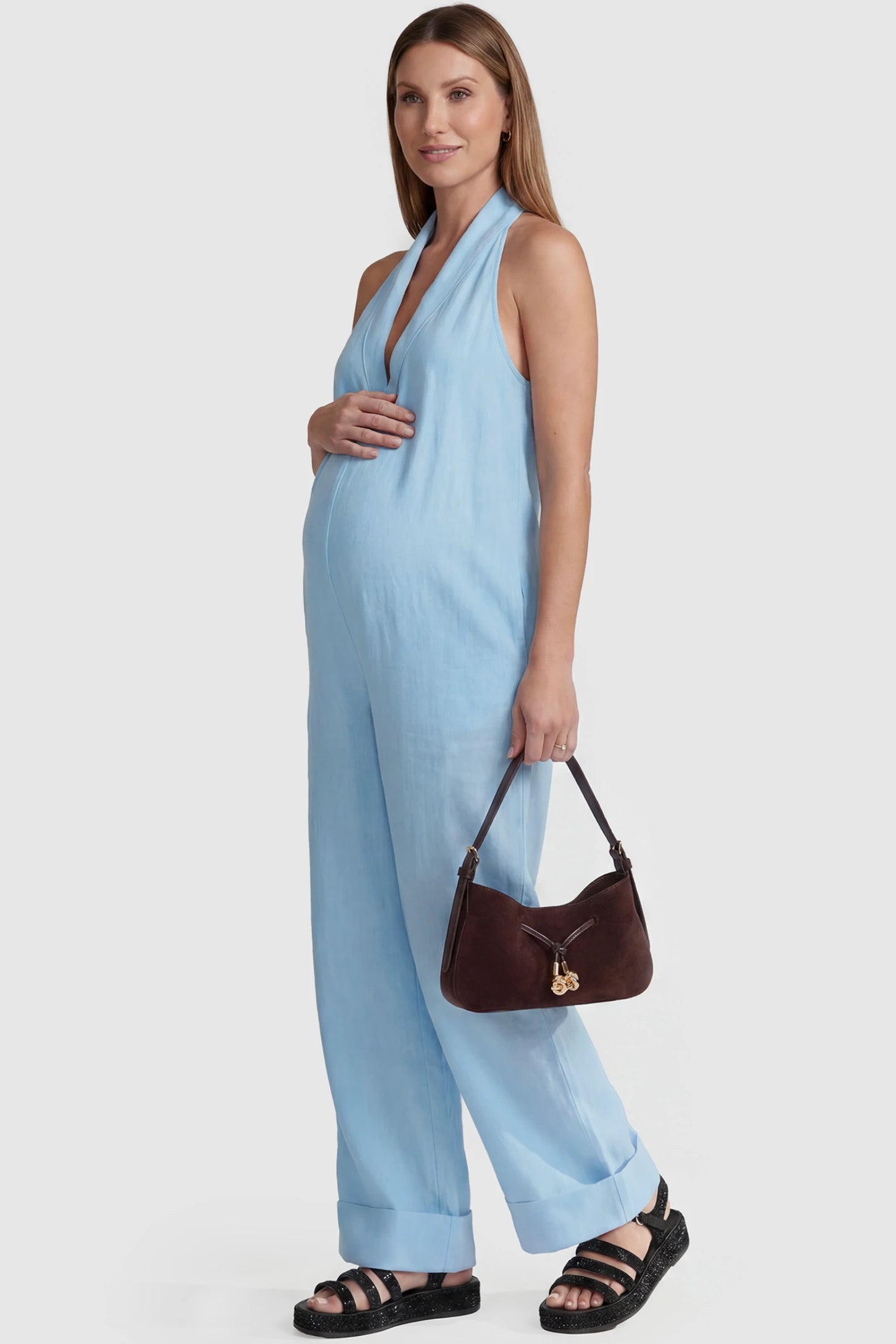 Halter Neck Wide-Leg Maternity Jumpsuit Halter neck wide-leg maternity jumpsuit in blue with chic halter neckline, side view on pregnant model