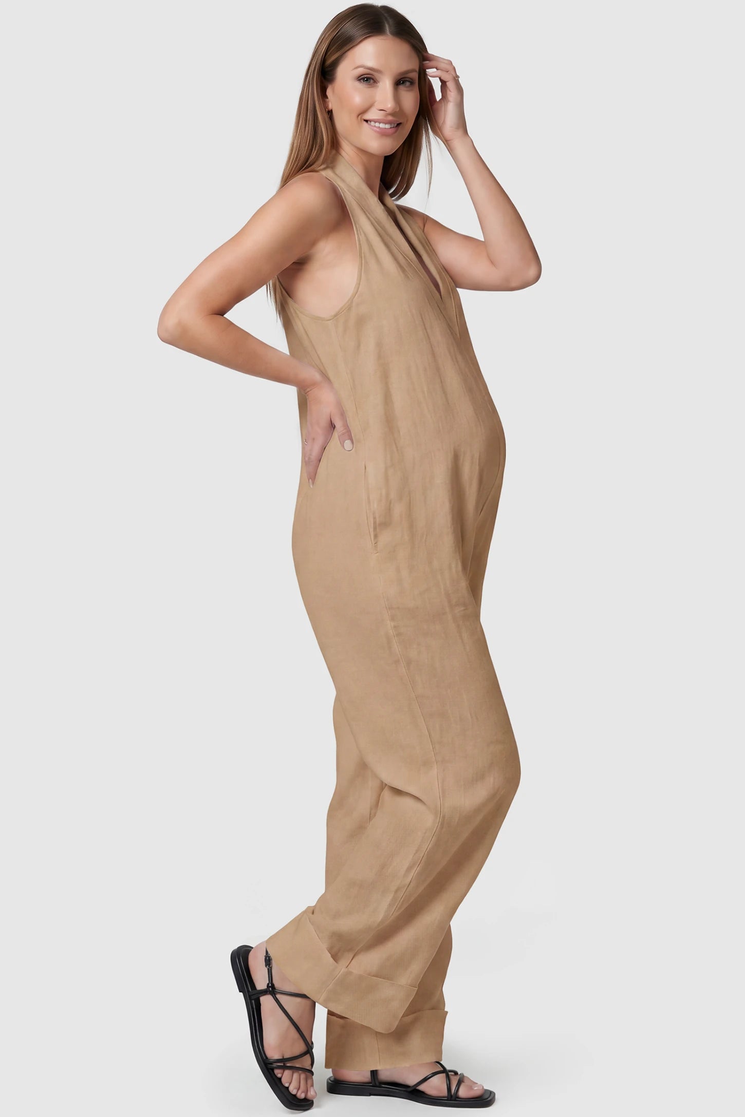 Halter Neck Wide-Leg Maternity Jumpsuit Halter neck wide-leg maternity jumpsuit in camel with sleeveless cut, side view on pregnant model