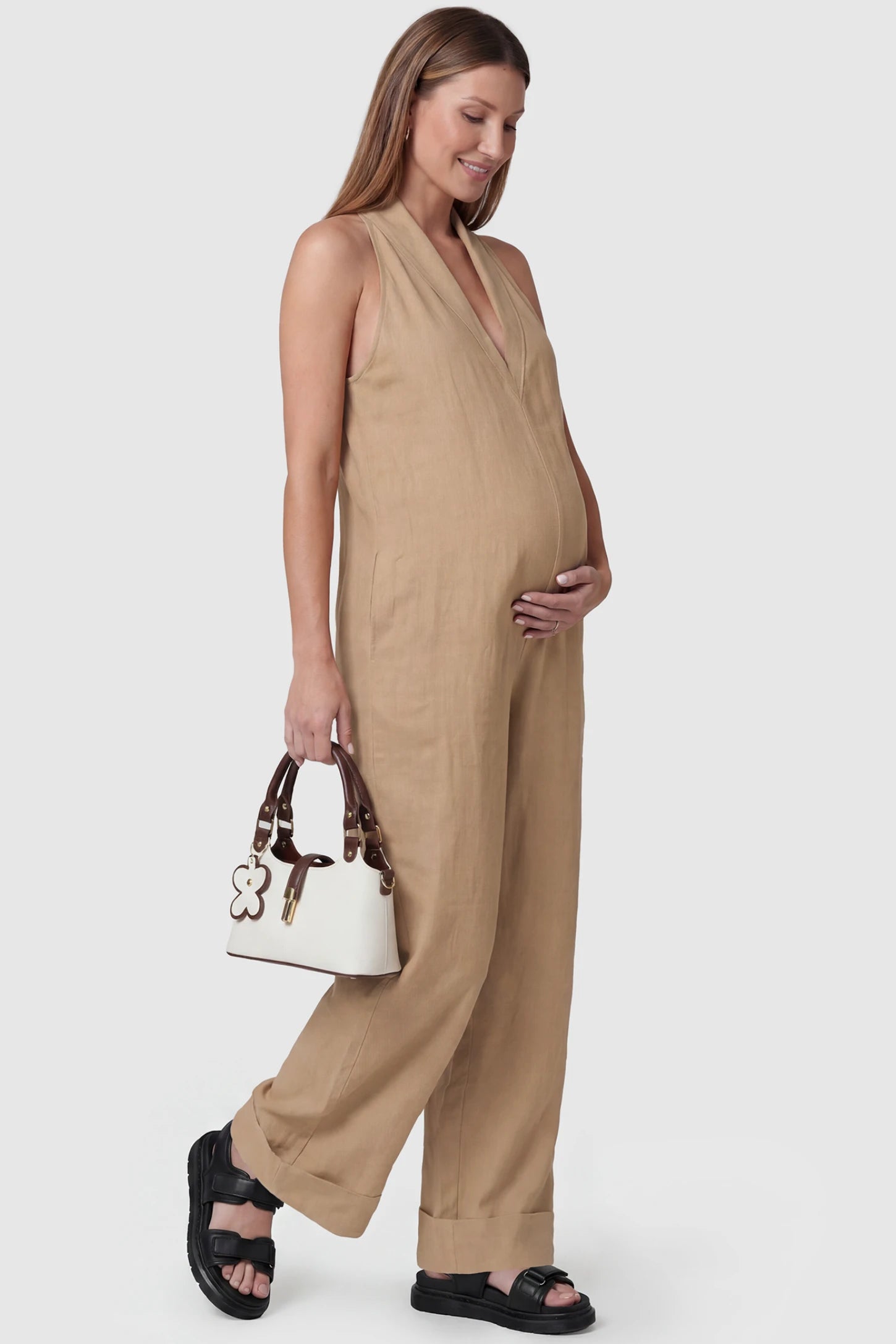 Halter Neck Wide-Leg Maternity Jumpsuit Halter neck wide-leg maternity jumpsuit in camel with chic halter neckline, side view on pregnant model
