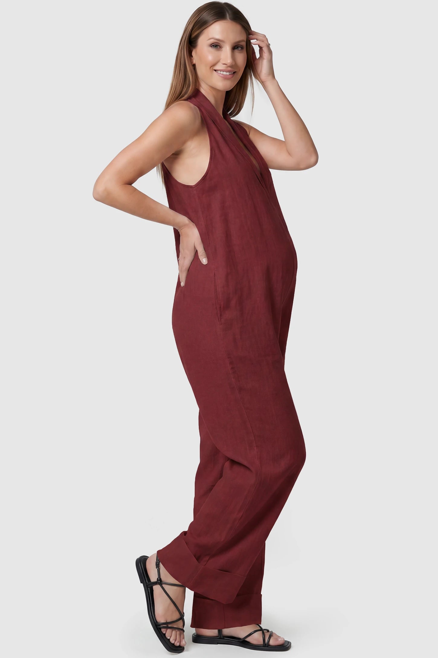 Halter Neck Wide-Leg Maternity Jumpsuit Halter neck wide-leg maternity jumpsuit in wine red with sleeveless cut, side view on pregnant model