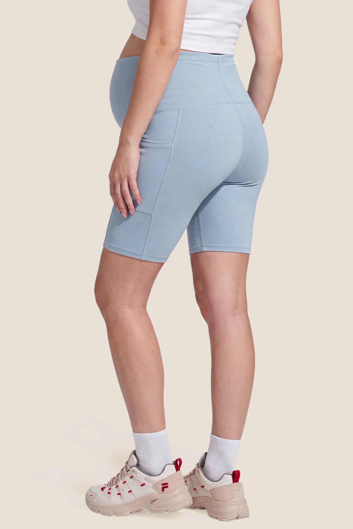 High-Rise Stretch Biker Maternity Shorts High-Rise Stretch Biker Maternity Shorts in Sky Blue featuring high-stretch fabric, seam-contoured fit, high-rise waistband, and mid-thigh active coverage on a pregnant model, back view.
