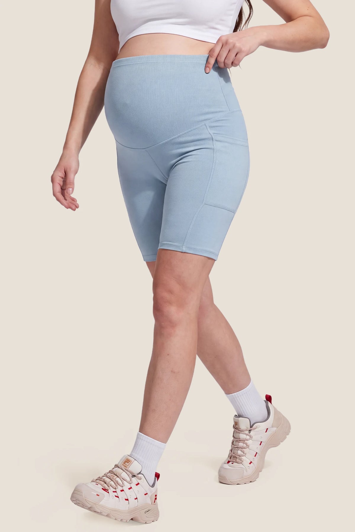High-Rise Stretch Biker Maternity Shorts High-Rise Stretch Biker Maternity Shorts in Sky Blue featuring full bump coverage, high-stretch jersey feel, ergonomic active fit, and supportive waistband on a pregnant model, front view.
