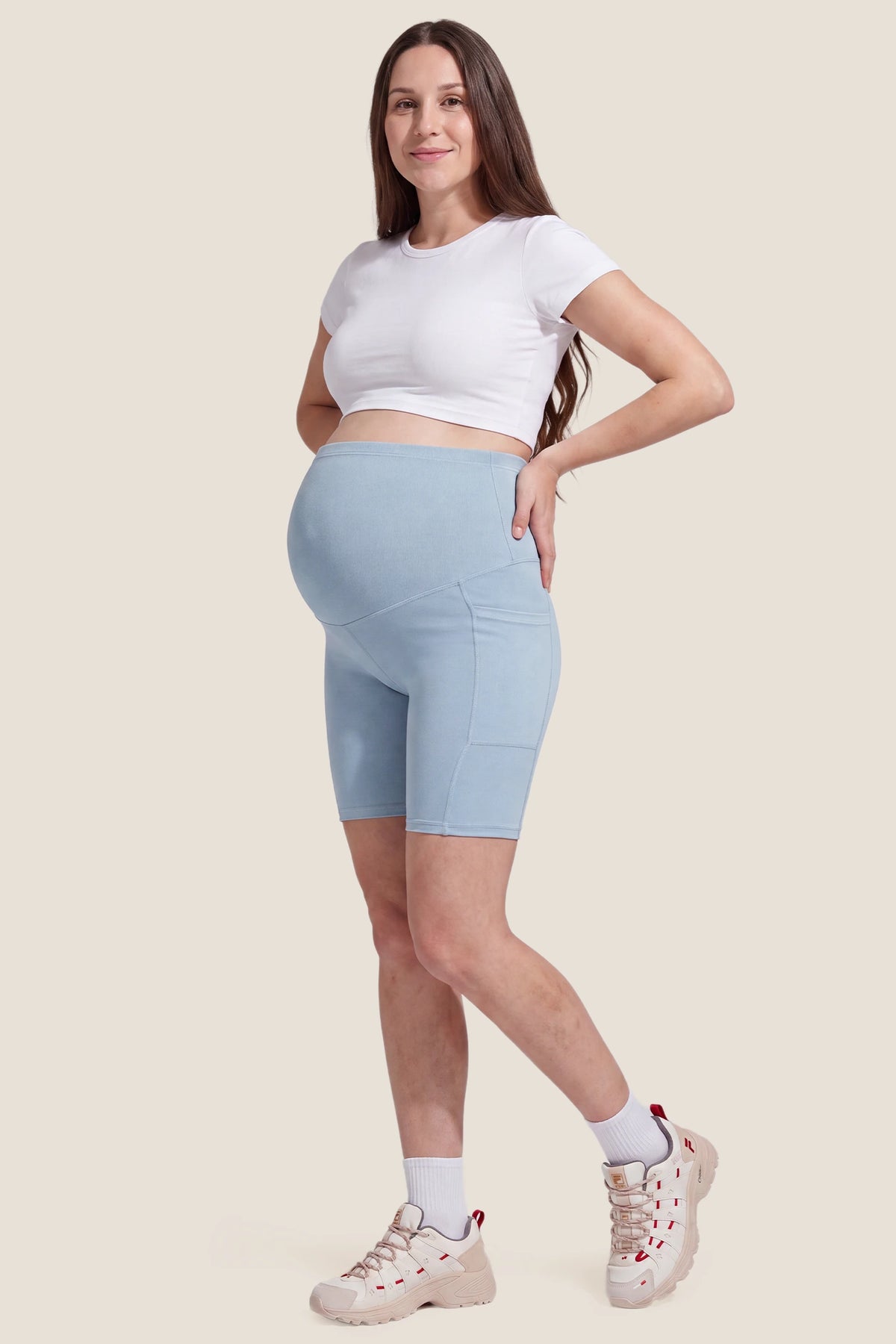 High-Rise Stretch Biker Maternity Shorts High-Rise Stretch Biker Maternity Shorts in Sky Blue featuring seam-contoured design, high-rise belly support panel, and comfortable maternity active shorts silhouette on a pregnant model, full body view.