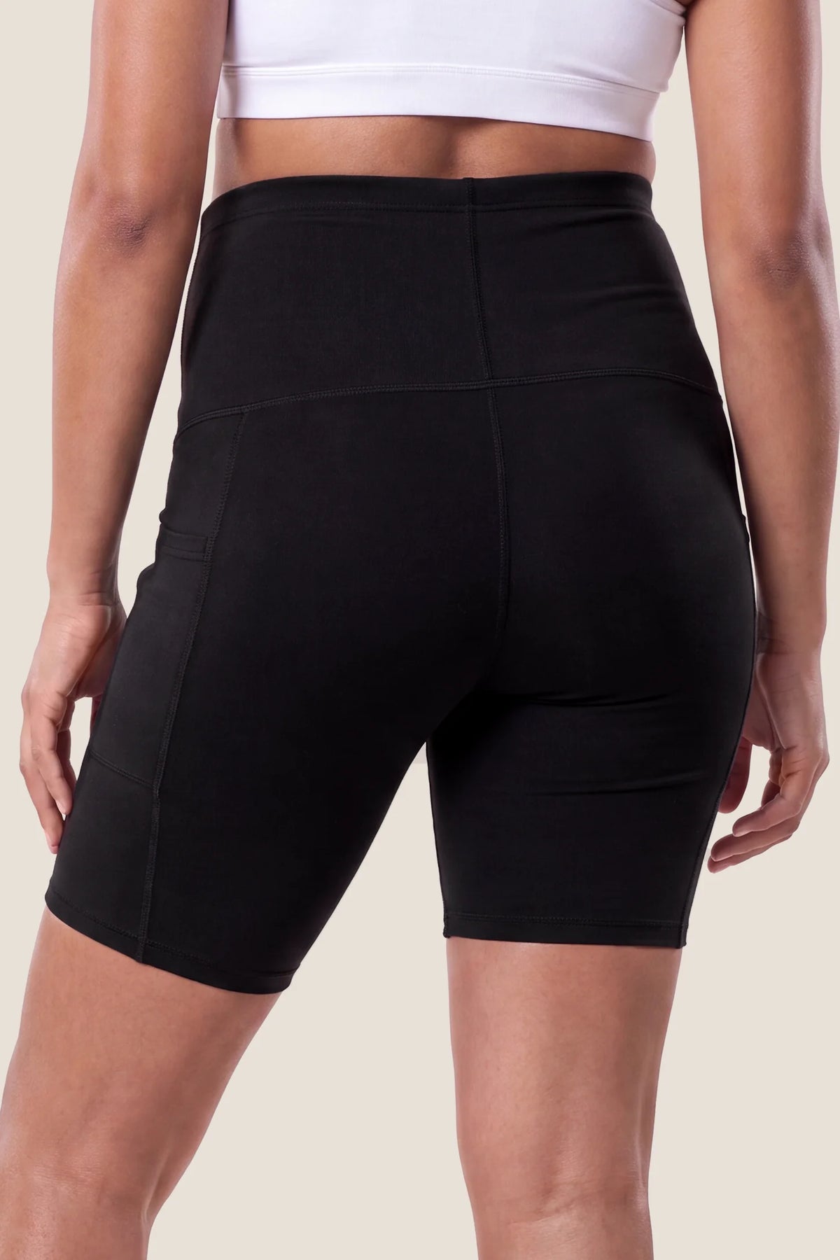 High-Rise Stretch Biker Maternity Shorts High-rise stretch biker maternity shorts in black featuring seamless fit, mid-thigh length, and supportive belly panel on pregnant model. back view