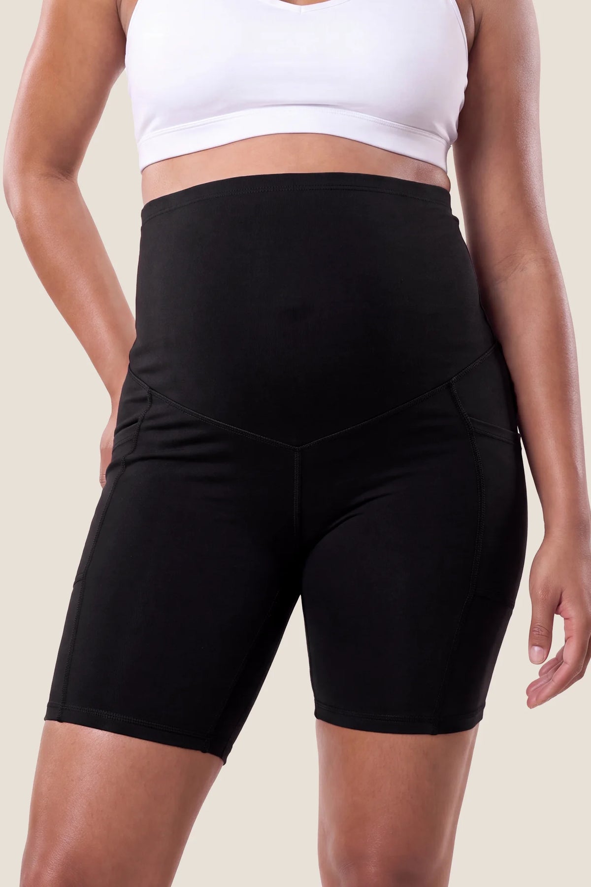High-Rise Stretch Biker Maternity Shorts High-rise stretch biker maternity shorts in black featuring seamless fit, mid-thigh length, and supportive belly panel on pregnant model. front view