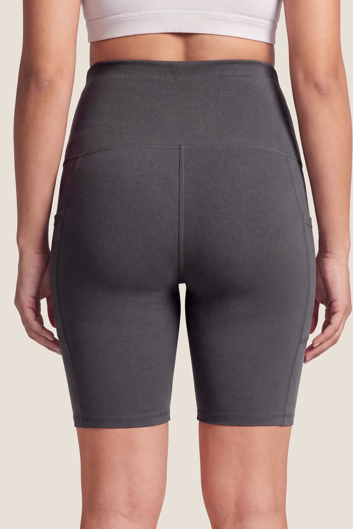 High-Rise Stretch Biker Maternity Shorts High-Rise-Stretch-Biker-Maternity-Shorts in Dark Gray featuring high-stretch fabric, seam-contoured fit, mid-thigh length, and a flattering backside silhouette on a pregnant model, back view.