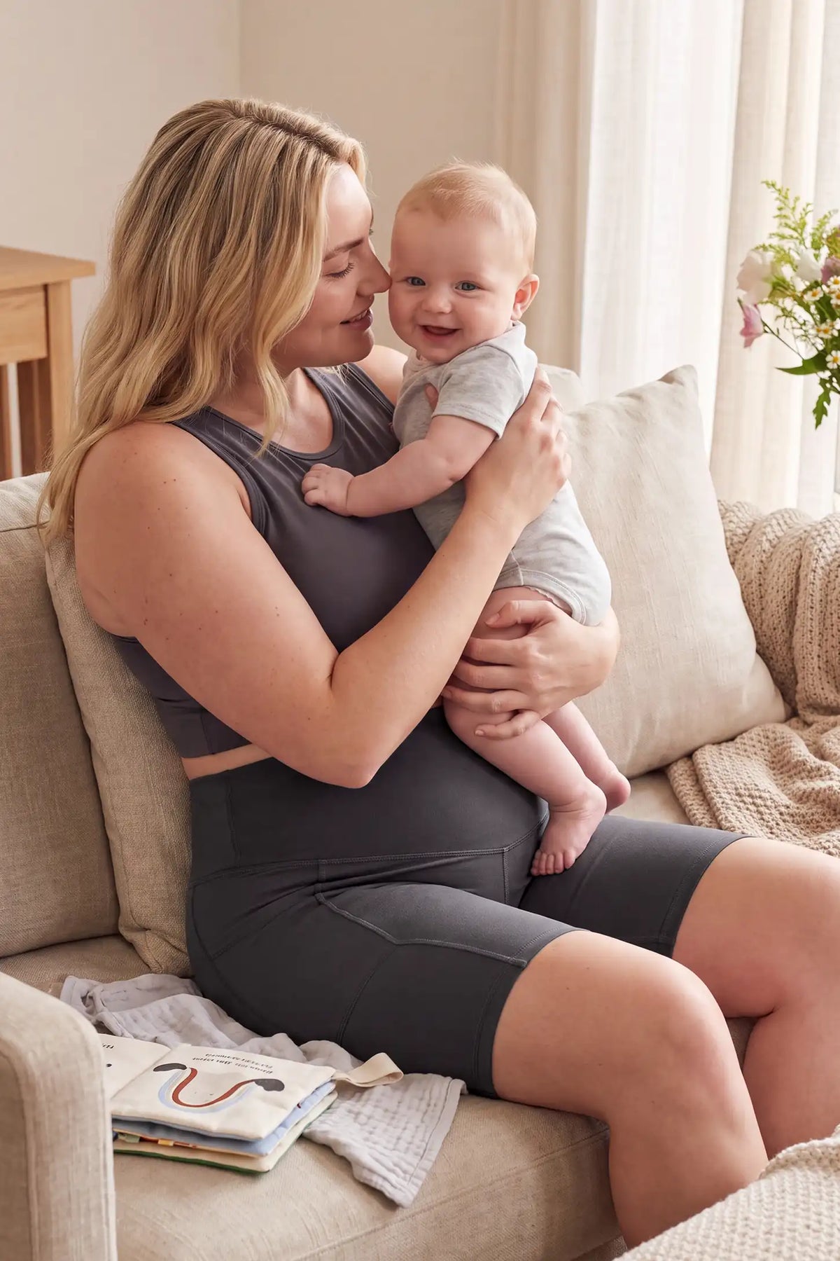 High-Rise Stretch Biker Maternity Shorts High-Rise Stretch Biker Maternity Shorts in Dark Gray featuring high-stretch fabric, soft breathable feel, and comfortable maternity loungewear style with a baby in a cozy indoor lifestyle setting.