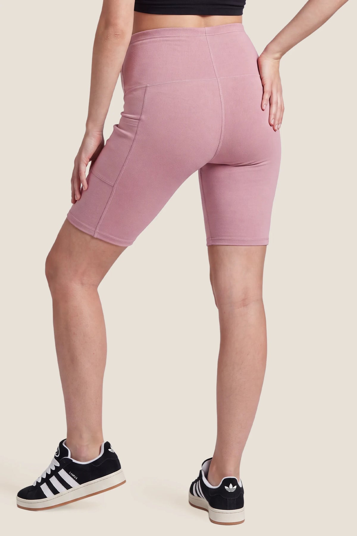 High-Rise Stretch Biker Maternity Shorts High-Rise Stretch Biker Maternity Shorts in Pink featuring high-stretch fabric, seam-contoured fit, high-rise belly coverage, and a mid-thigh active silhouette on a pregnant model, back view.