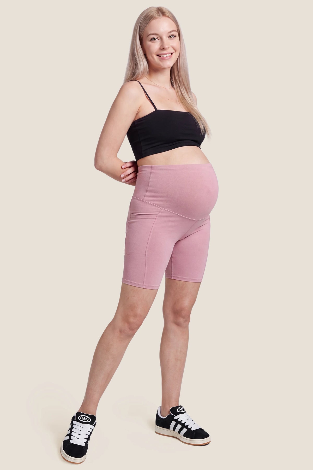 High-Rise Stretch Biker Maternity Shorts High-Rise Stretch Biker Maternity Shorts in Pink featuring flexible high-stretch coverage, supportive high-waist fit, and casual maternity shorts style on a pregnant model, full body view.