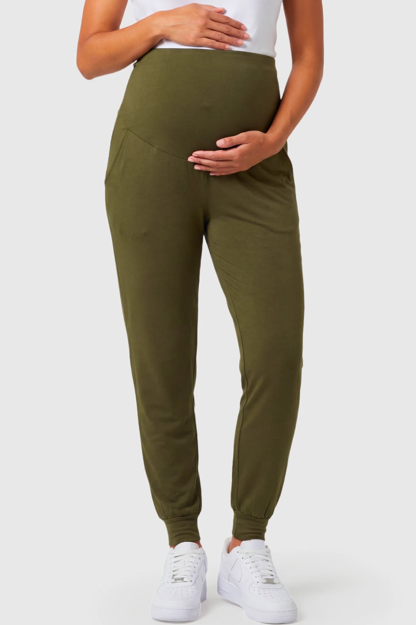 Full-Panel Cuffed Maternity Joggers Full-Panel Cuffed Maternity Joggers in army green featuring high-rise over-the-belly panel, ribbed cuff hem, and side pockets on pregnant model.