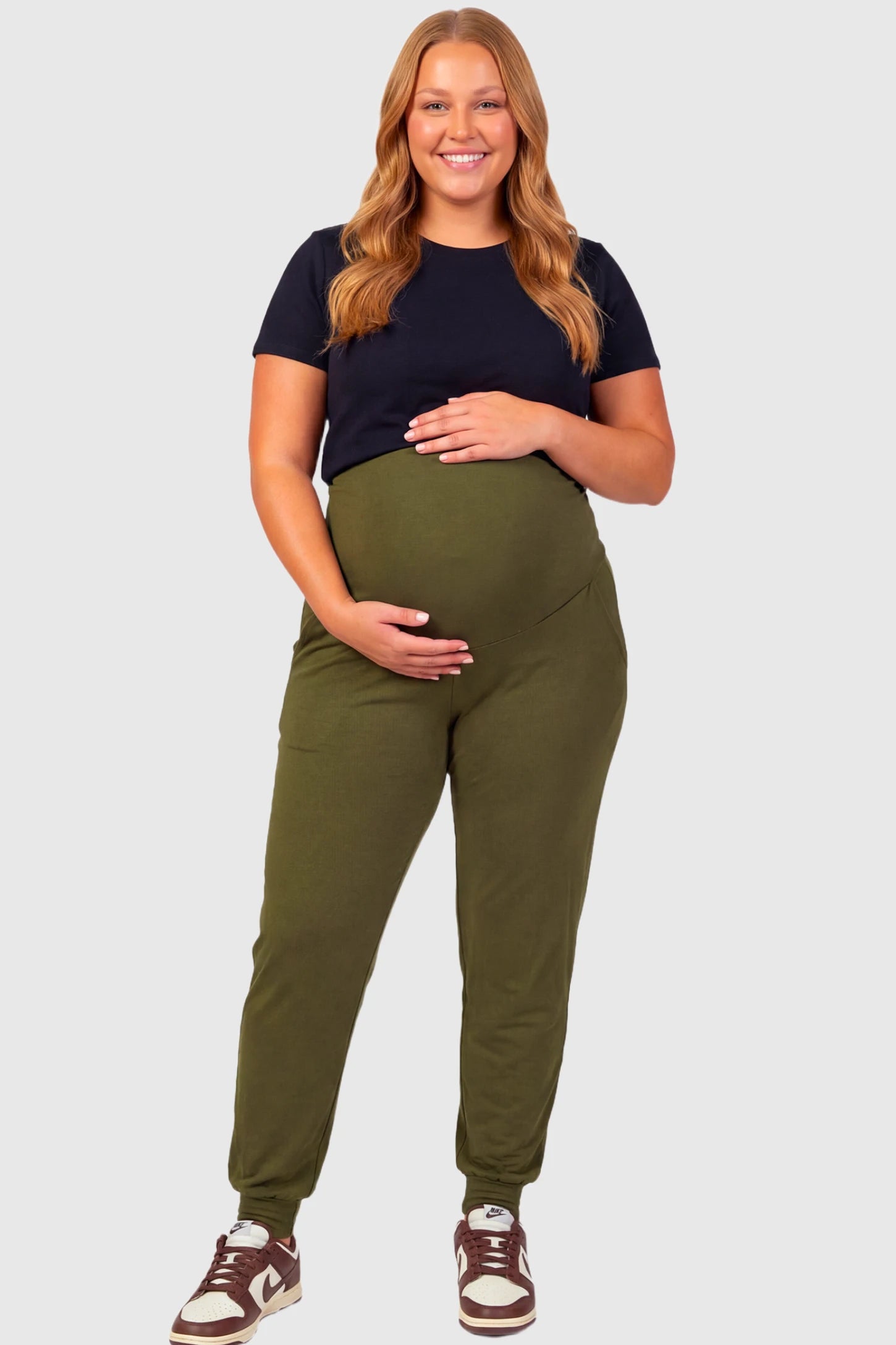 Full-Panel Cuffed Maternity Joggers Full-Panel Cuffed Maternity Joggers in army green featuring high-rise over-the-belly panel, ribbed cuff hem, and side pockets on plus size pregnant model.