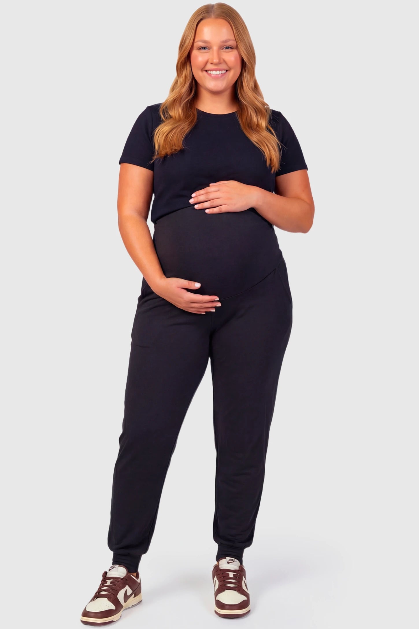 Full-Panel Cuffed Maternity Joggers Full-Panel Cuffed Maternity Joggers in black featuring high-rise over-the-belly panel, ribbed cuff hem, and side pockets on plus size pregnant model.