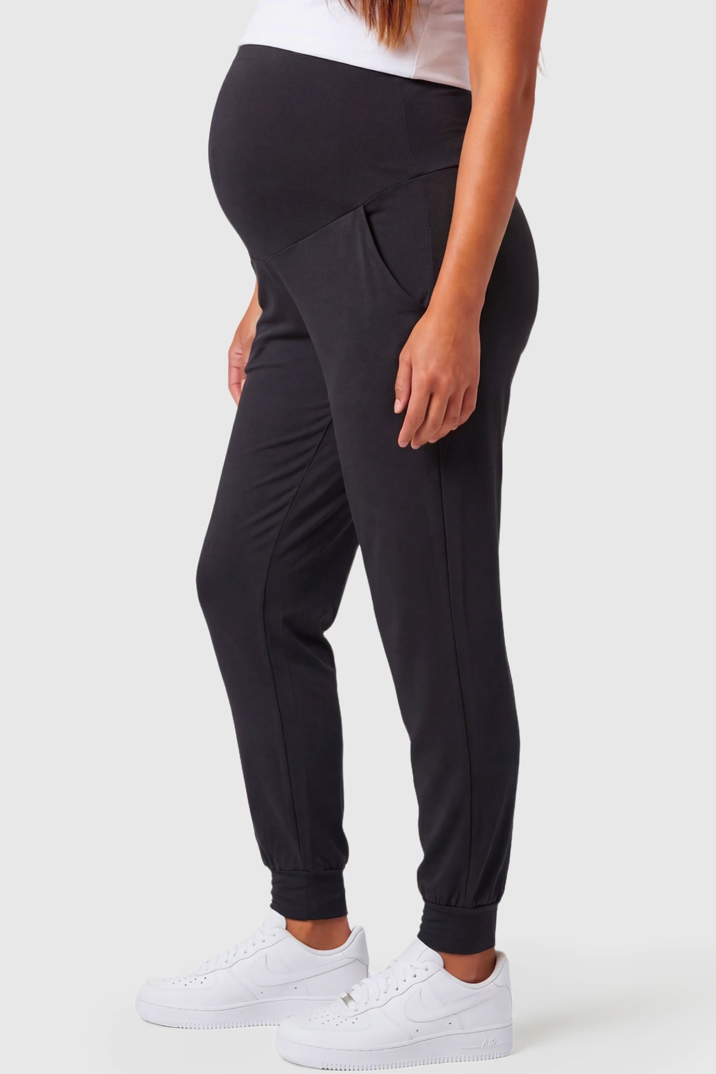 Full-Panel Cuffed Maternity Joggers Full-Panel Cuffed Maternity Joggers in black featuring high-rise over-the-belly panel, ribbed cuff hem, and side pockets on pregnant model.