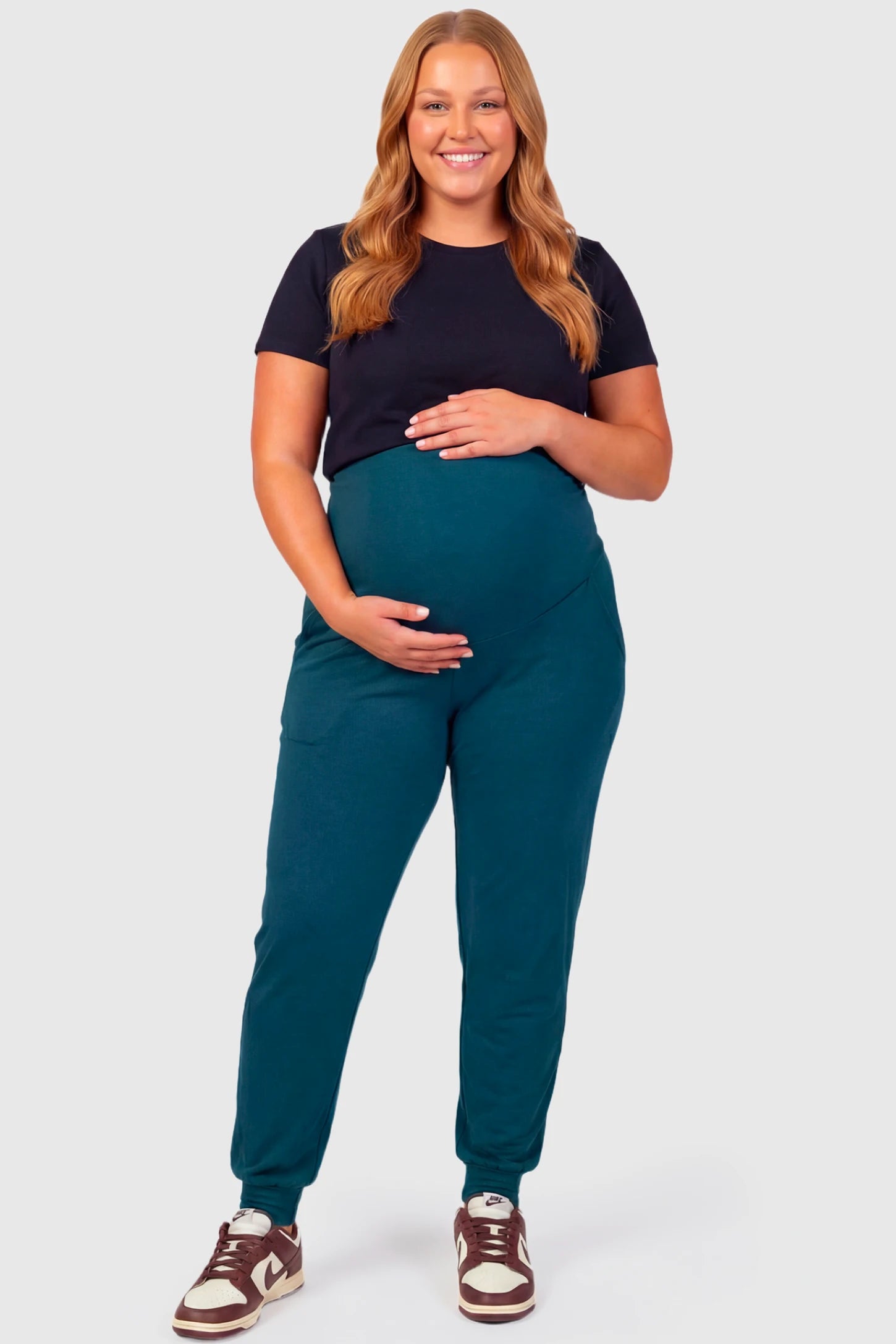 Full-Panel Cuffed Maternity Joggers Full-Panel Cuffed Maternity Joggers in blue featuring high-rise over-the-belly panel, ribbed cuff hem, and side pockets on plus size pregnant model.