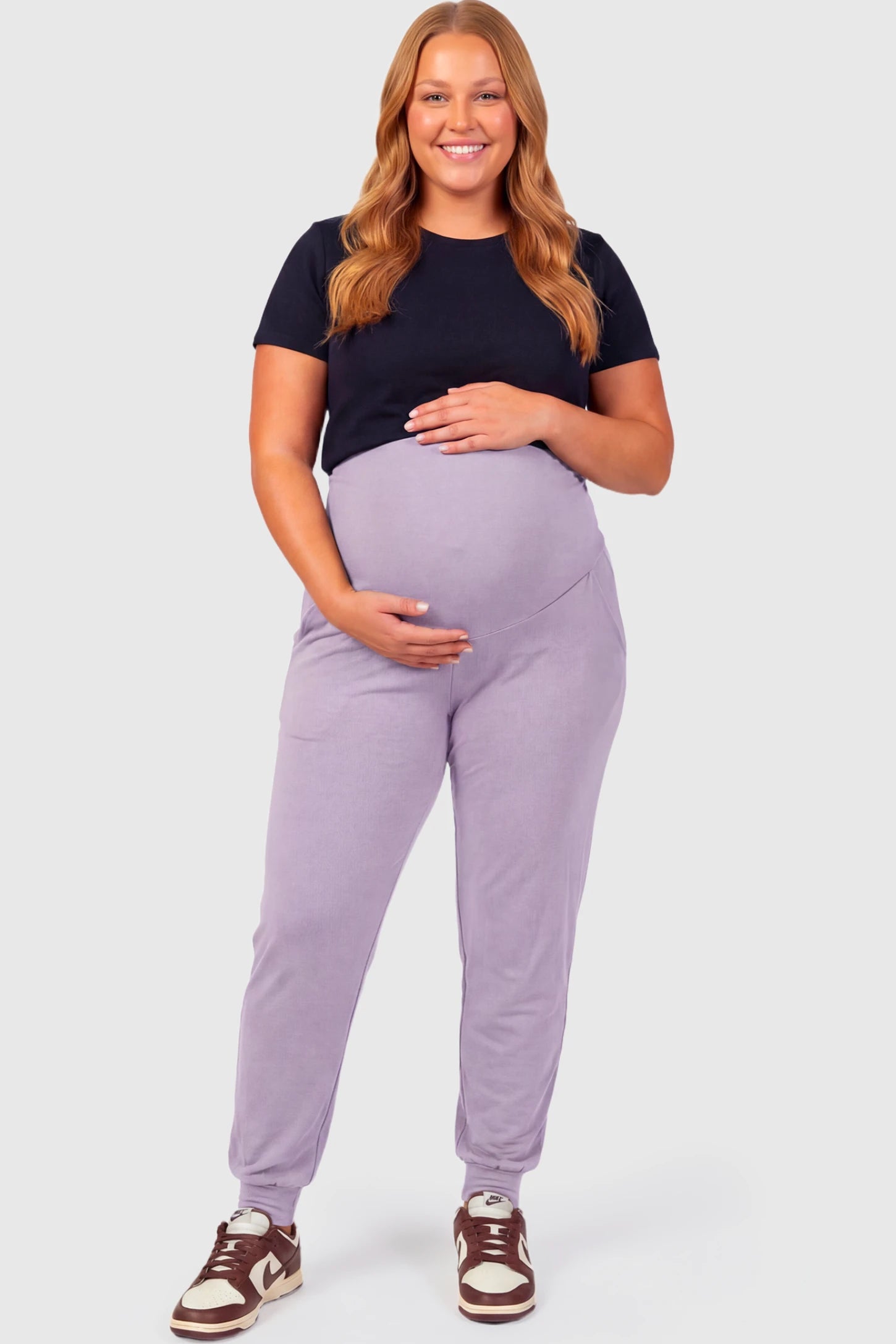 Full-Panel Cuffed Maternity Joggers Full-Panel Cuffed Maternity Joggers in lavender featuring high-rise over-the-belly panel, ribbed cuff hem, and side pockets on plus size pregnant model.