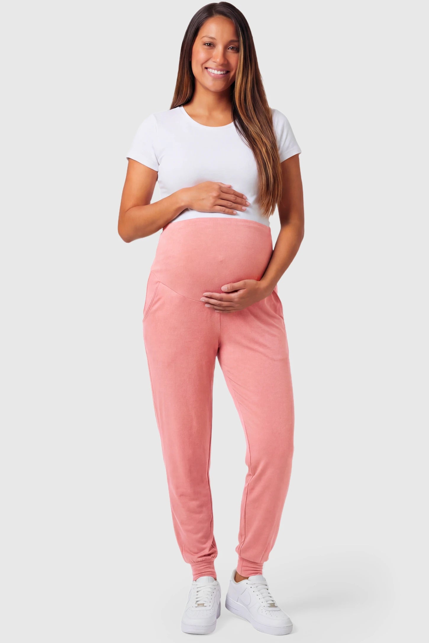 Full-Panel Cuffed Maternity Joggers Full-Panel Cuffed Maternity Joggers in pink featuring high-rise over-the-belly panel, ribbed cuff hem, and side pockets on pregnant model.