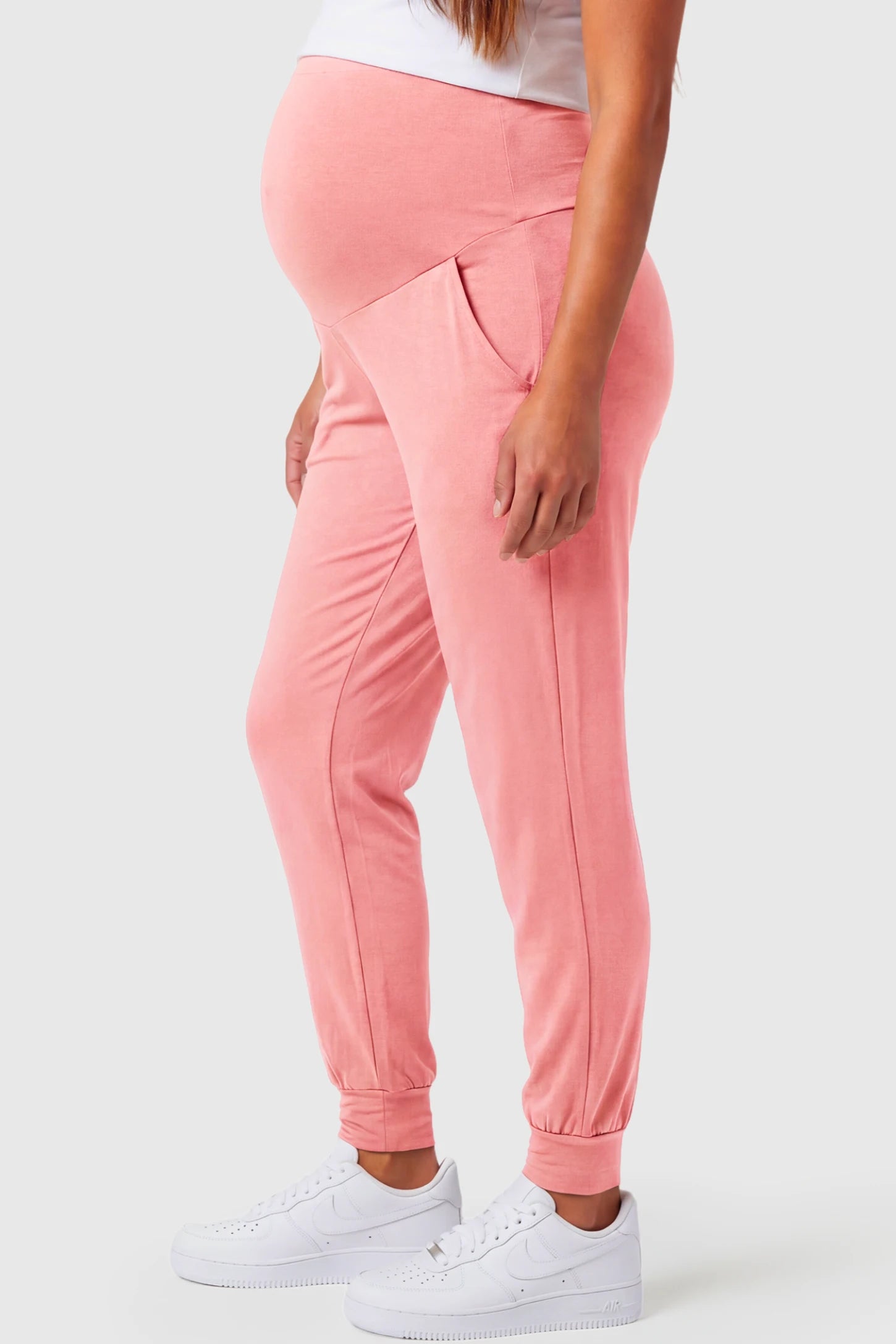 Full-Panel Cuffed Maternity Joggers Full-Panel Cuffed Maternity Joggers in pink featuring high-rise over-the-belly panel, ribbed cuff hem, and side pockets on pregnant model.