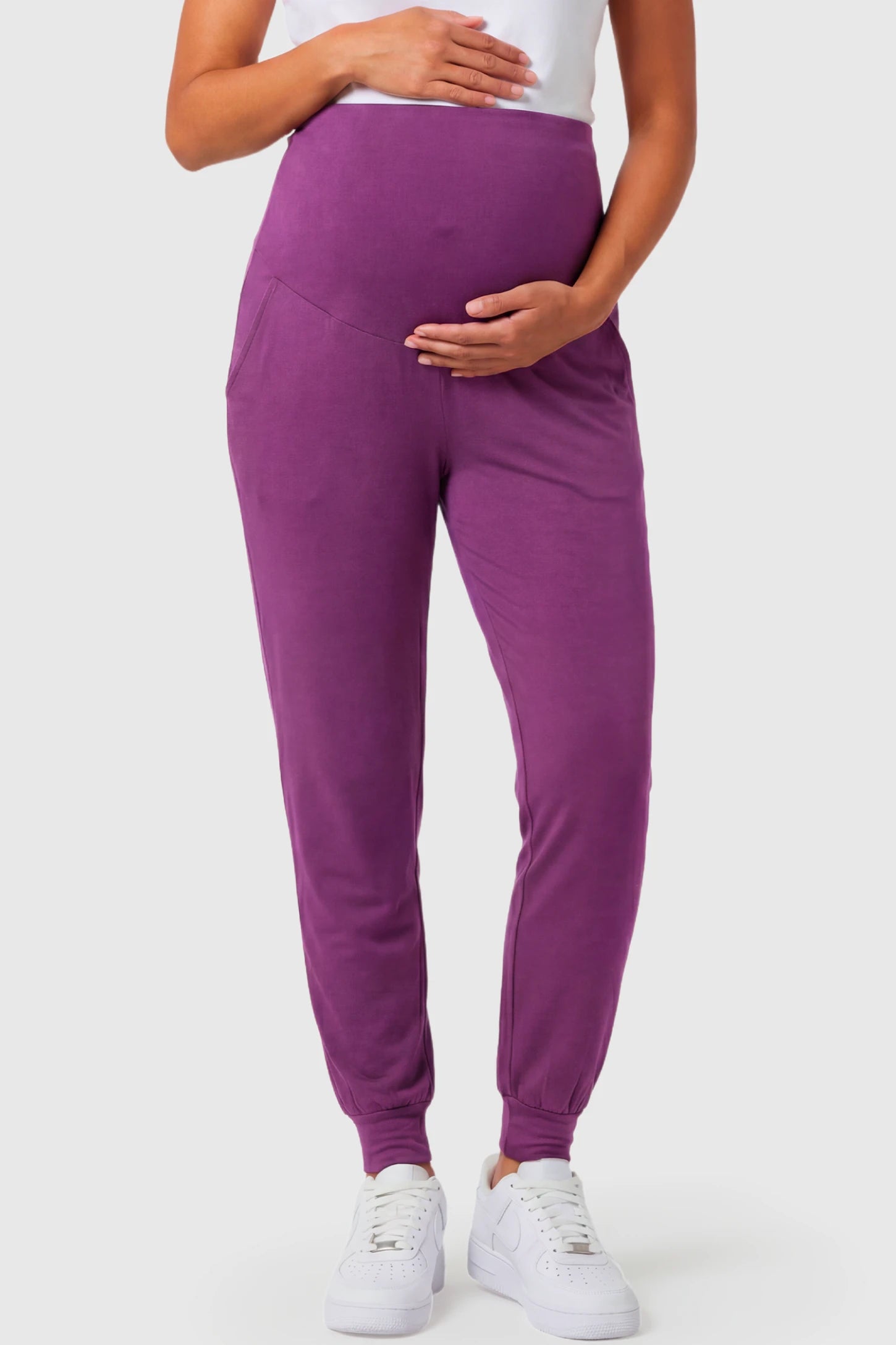 Full-Panel Cuffed Maternity Joggers Full-Panel Cuffed Maternity Joggers in purple featuring high-rise over-the-belly panel, ribbed cuff hem, and side pockets on pregnant model.