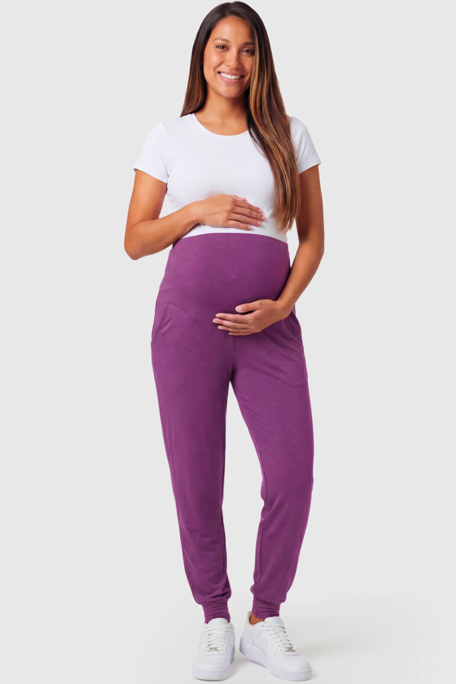 Full-Panel Cuffed Maternity Joggers Full-Panel Cuffed Maternity Joggers in purple featuring high-rise over-the-belly panel, ribbed cuff hem, and side pockets on pregnant model.