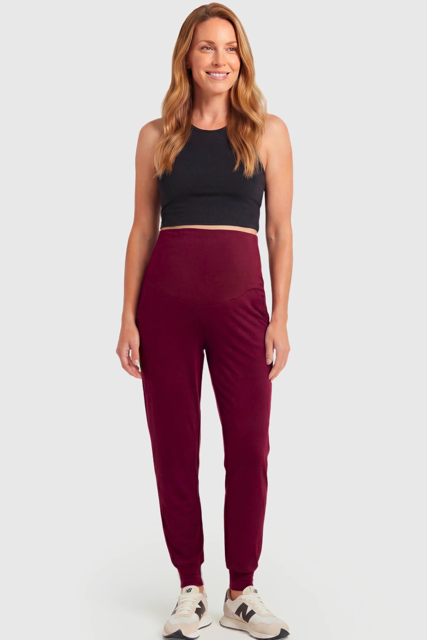 Full-Panel Cuffed Maternity Joggers Full-Panel Cuffed Maternity Joggers in wine red featuring high-rise over-the-belly panel, ribbed cuff hem, and side pockets on pregnant model.