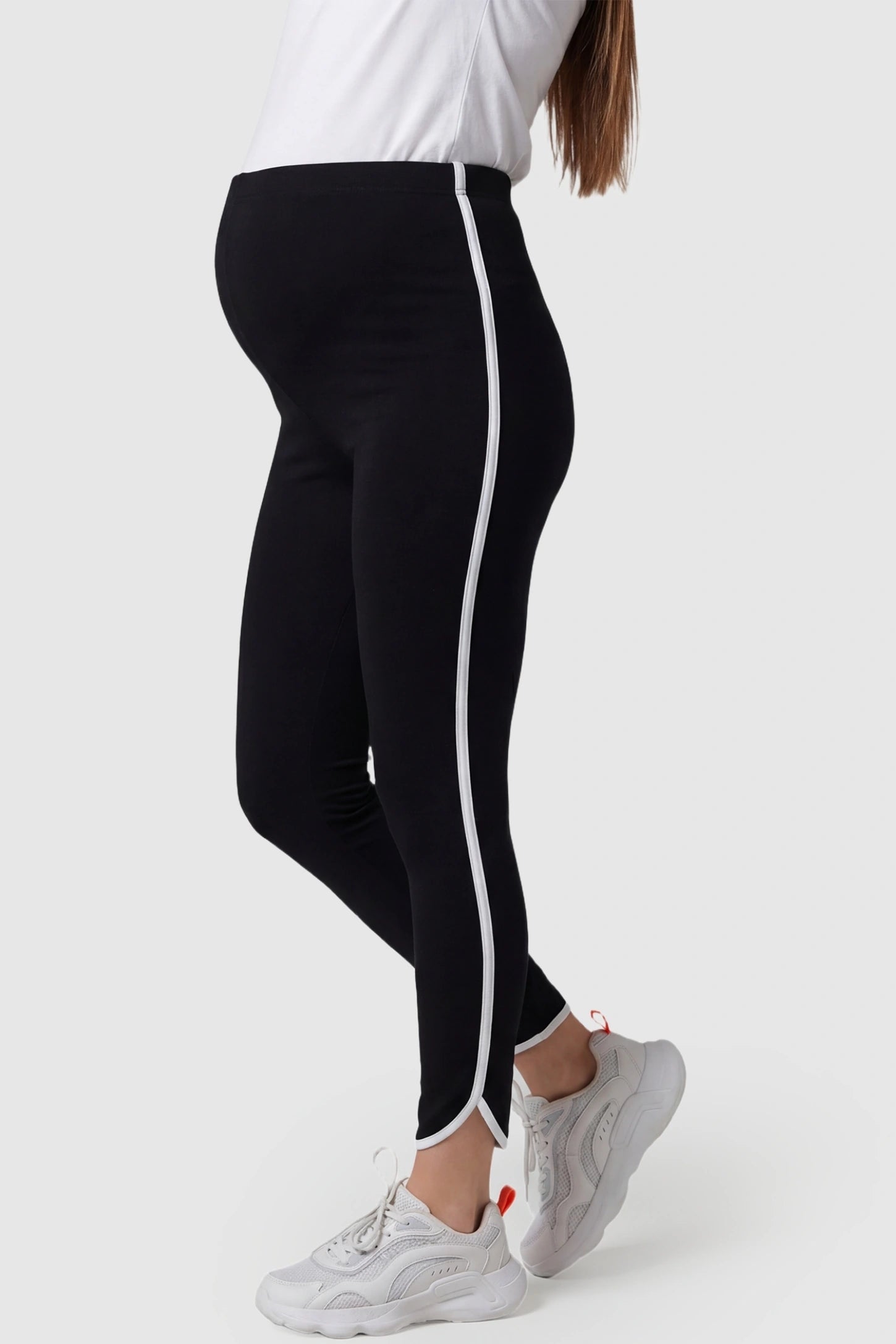 Shaping Side-Stripe Maternity Leggings High Waisted Side Stripe Maternity Leggings in black featuring decorative white side stripes on a pregnant model from the side.