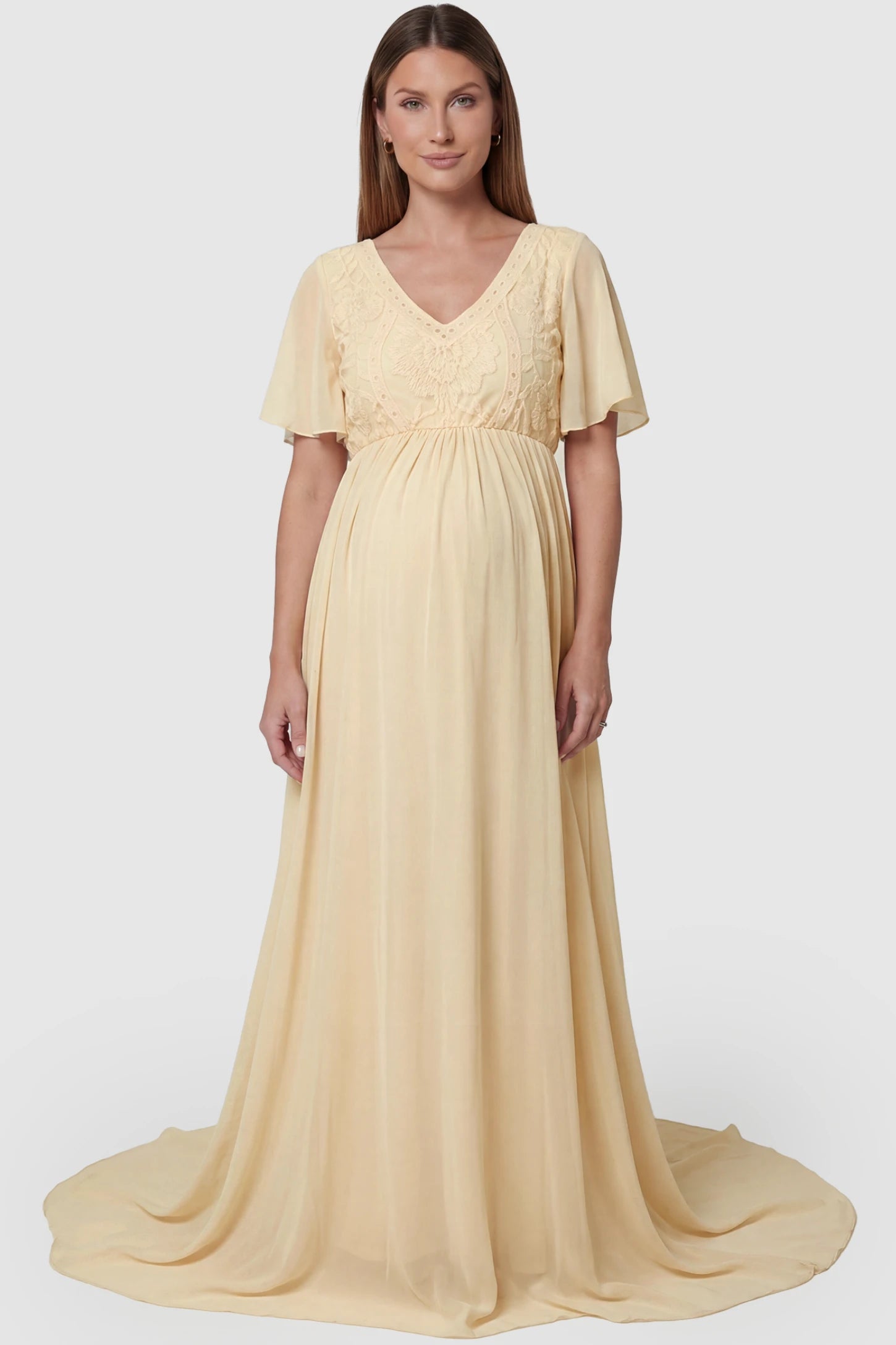Lace Embroidered Short Flutter Sleeve Maternity Gown Lace embroidered short flutter sleeve maternity gown in apricot with delicate lace embroidery & flutter sleeves, front view on pregnant model