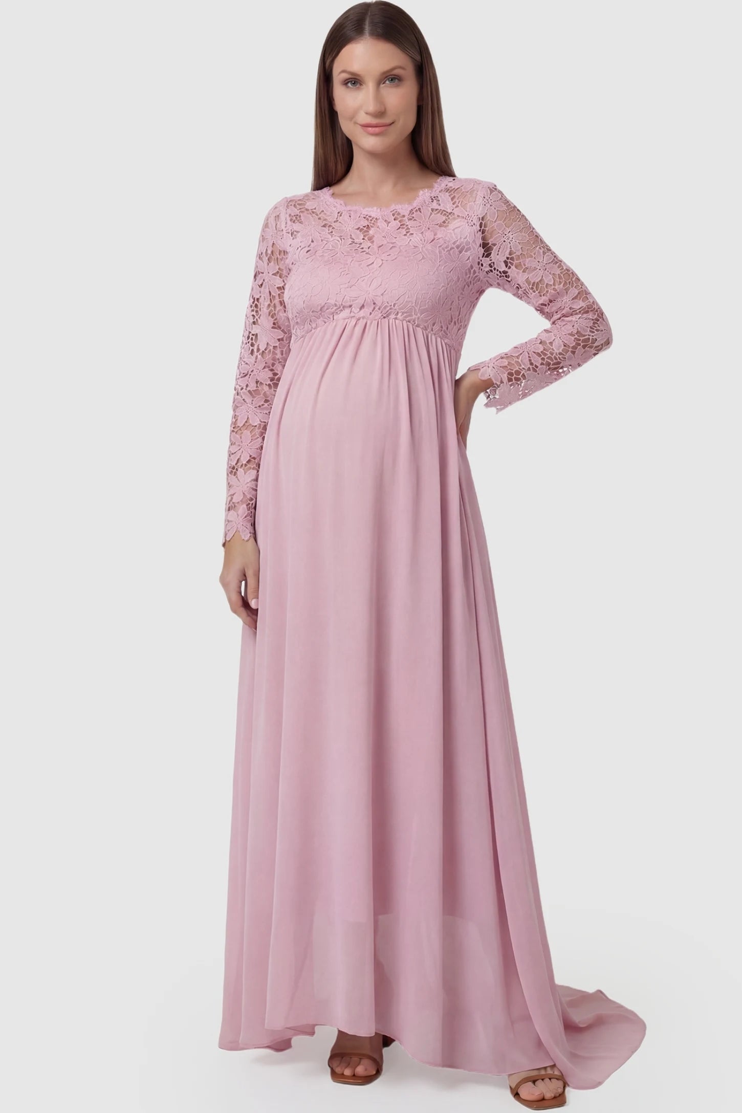 Lace long sleeve full skirt maxi maternity dress in pink featuring empire waist in full body front view on a pregnant model
