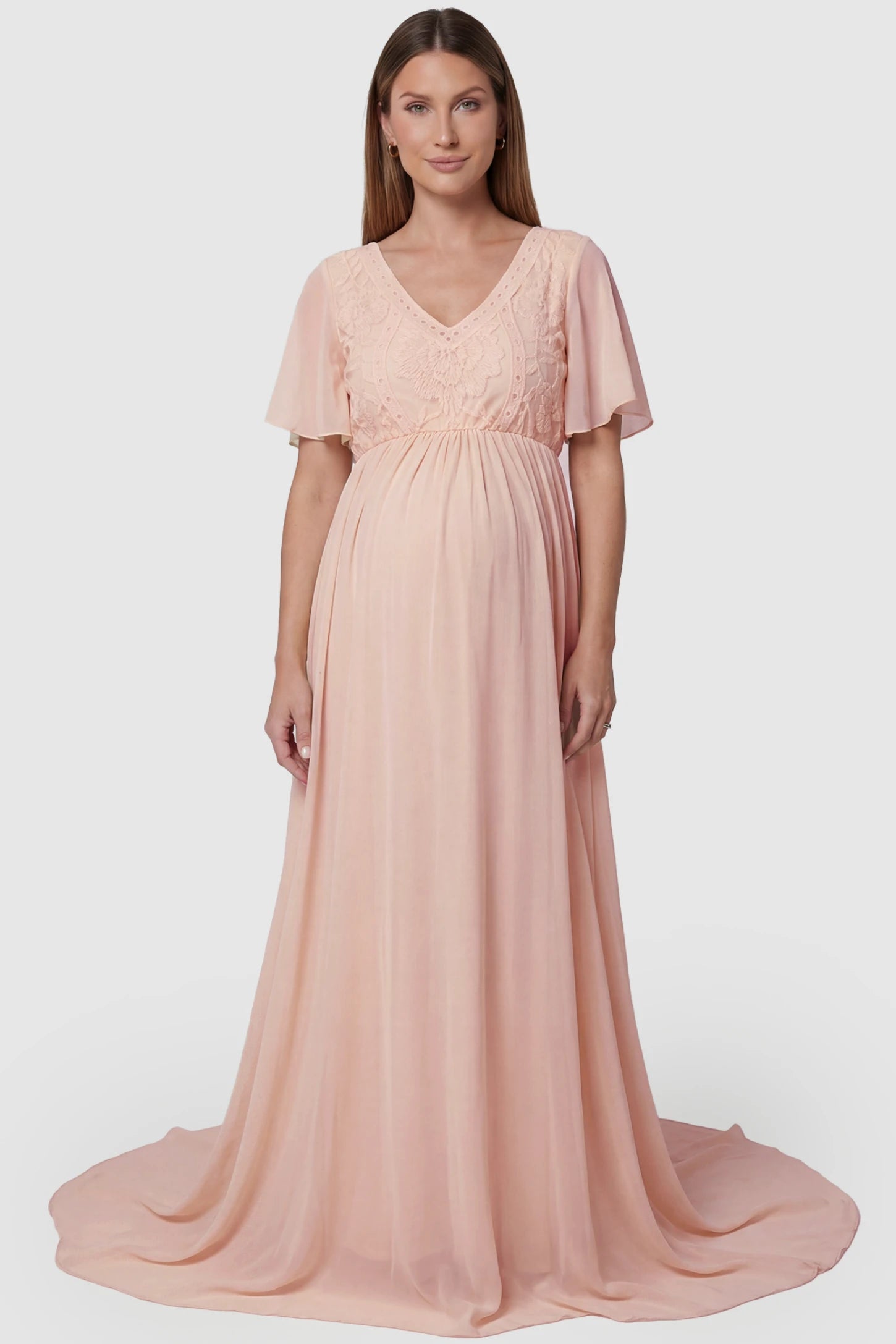 Lace Embroidered Short Flutter Sleeve Maternity Gown Lace embroidered short flutter sleeve maternity gown in pink with delicate lace embroidery & flutter sleeves, front view on pregnant model