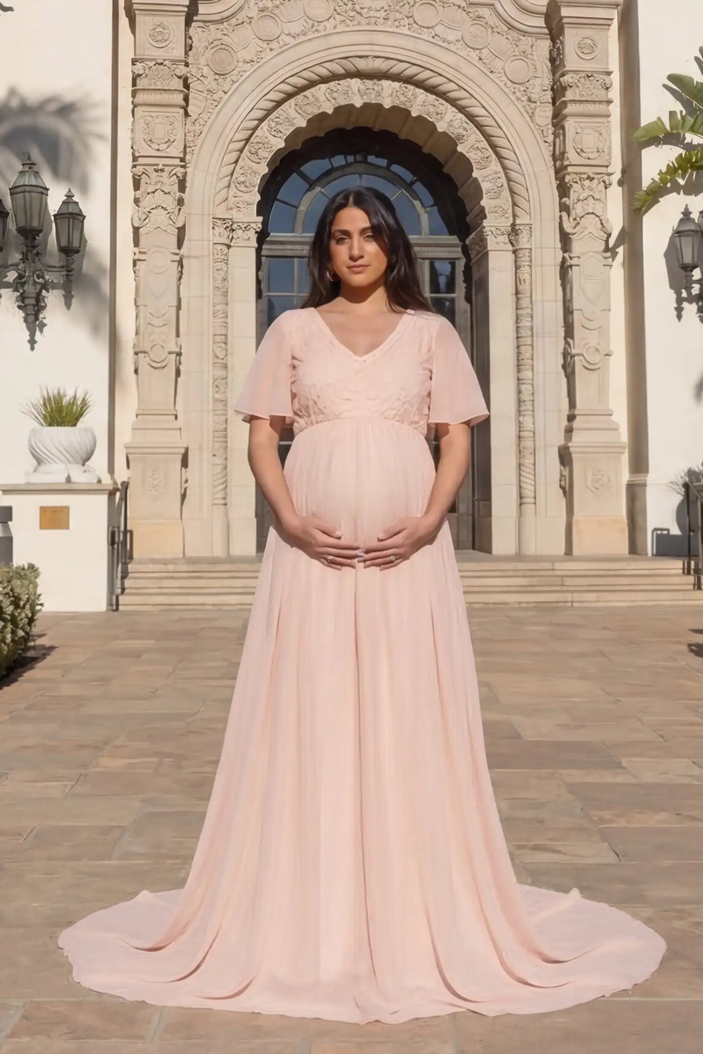 Lace Embroidered Short Flutter Sleeve Maternity Gown Lace embroidered short flutter sleeve maternity gown in pink with delicate lace embroidery & flutter sleeves, front view on pregnant model