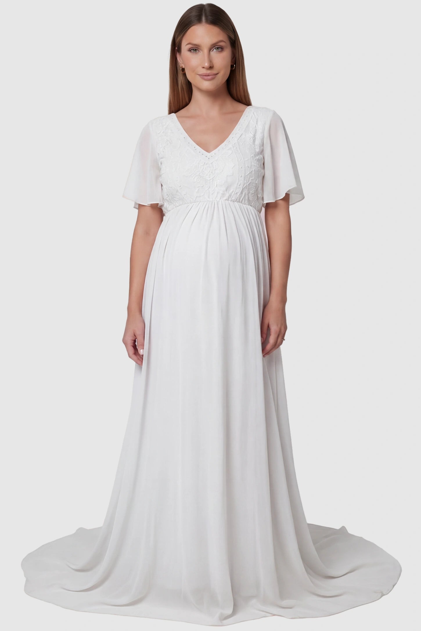 Lace embroidered short flutter sleeve maternity gown in white with delicate lace embroidery & flutter sleeves, front view on pregnant model
