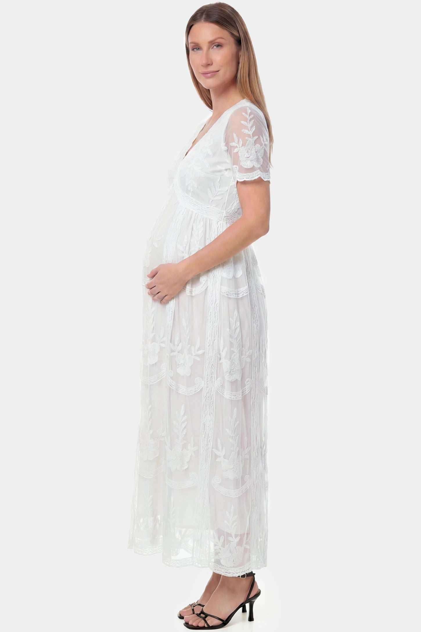 Lace Short Sheer Sleeve Maternity Maxi Dress Lace Short Sheer Sleeve Maternity Maxi Dress in white lace featuring sheer short sleeves and an empire waist silhouette on a pregnant model.