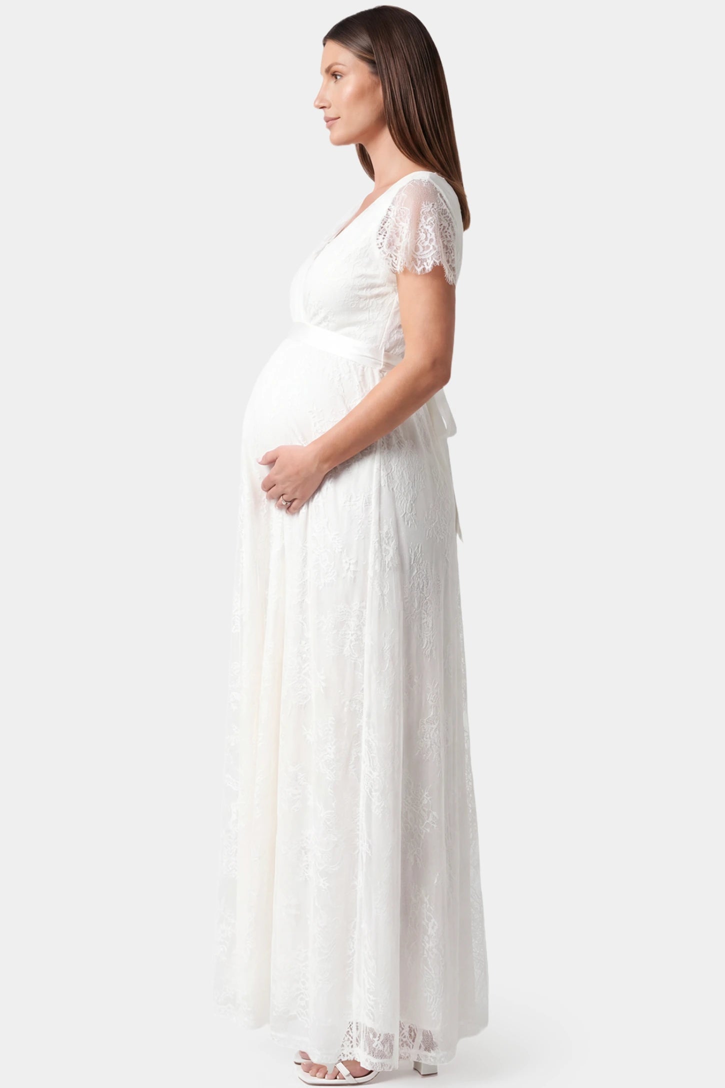 Lace flutter sleeve V-neck maxi maternity dress in white featuring soft flutter sleeves in side view on a pregnant model