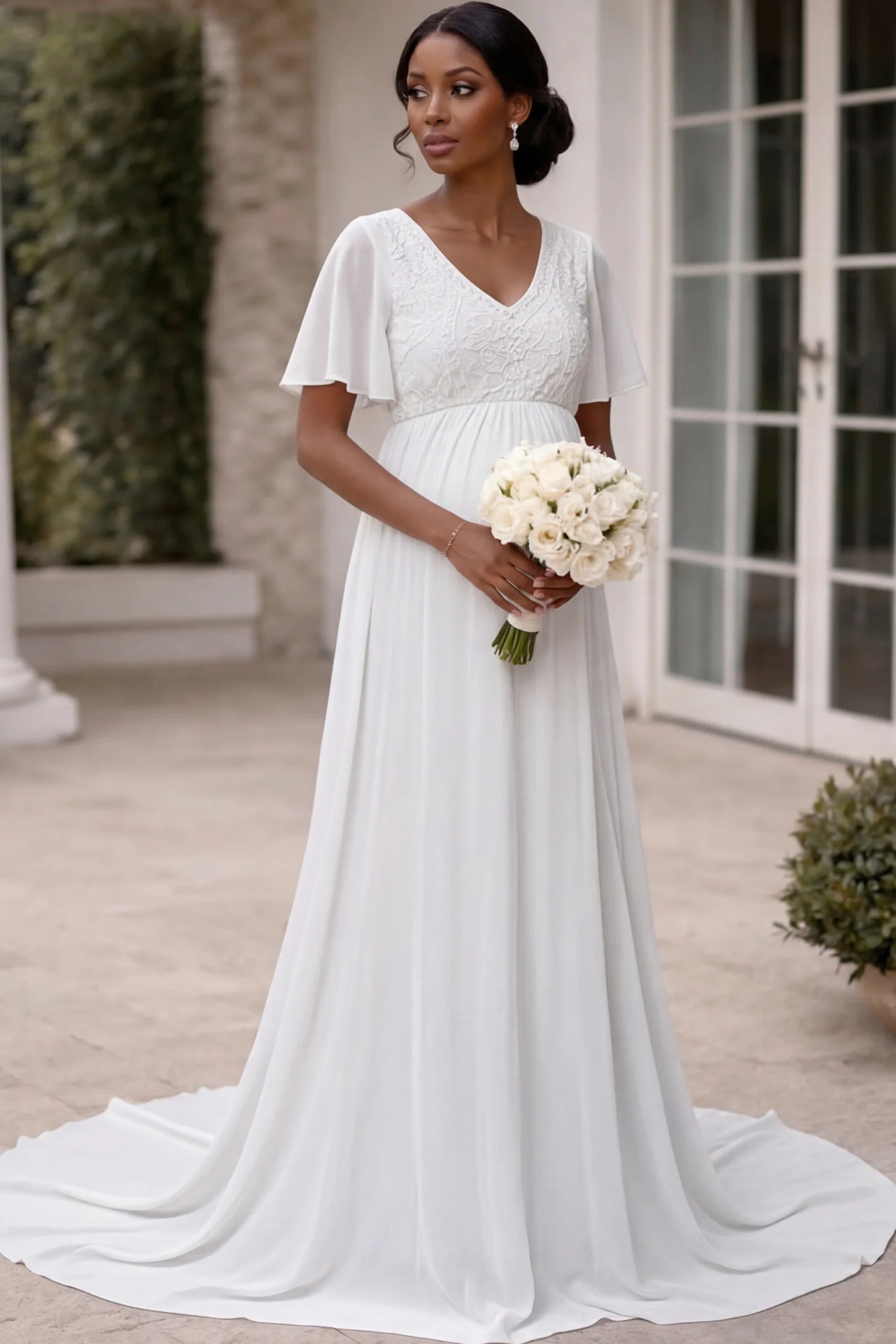 Lace embroidered short flutter sleeve maternity gown in white with delicate lace embroidery & flutter sleeves, front view on pregnant model